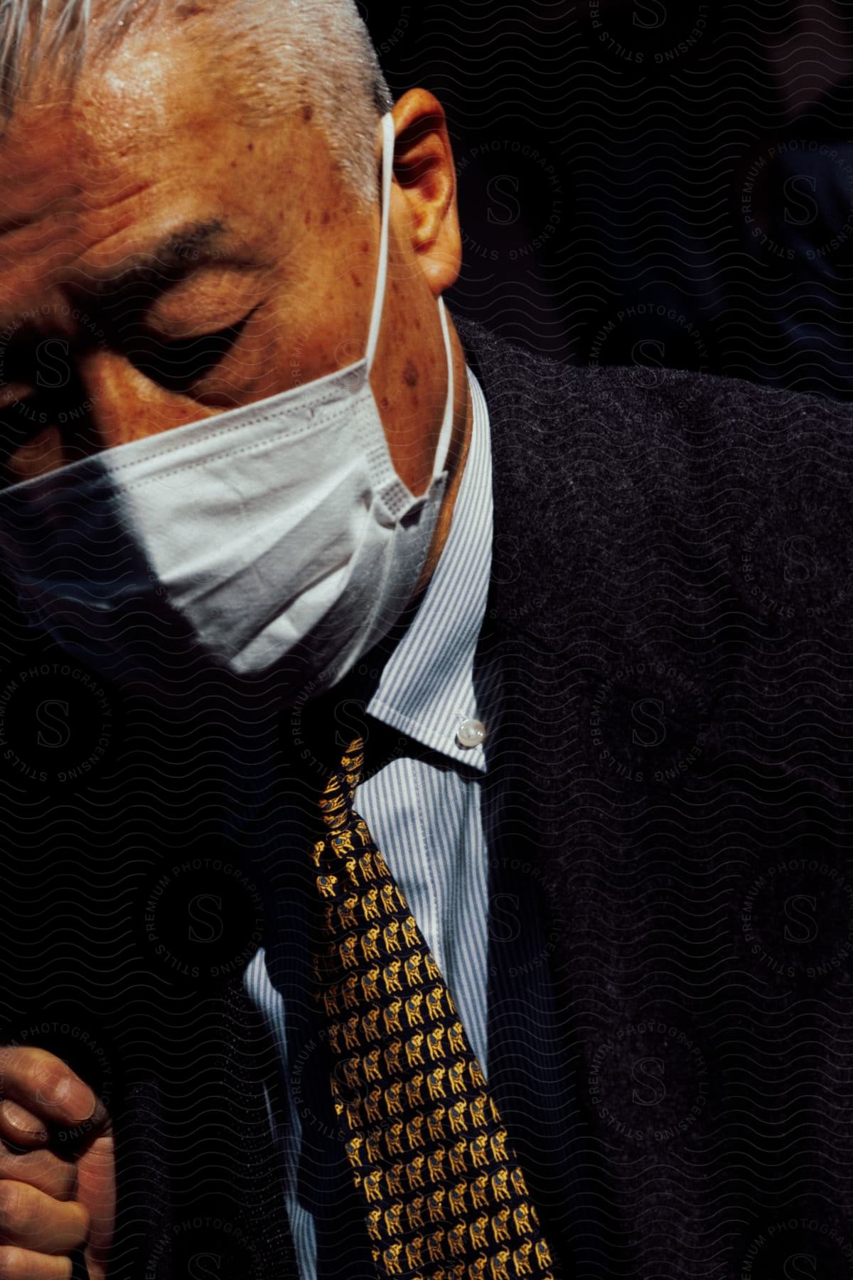 A man wearing a suit and tie with a mask obscuring his face