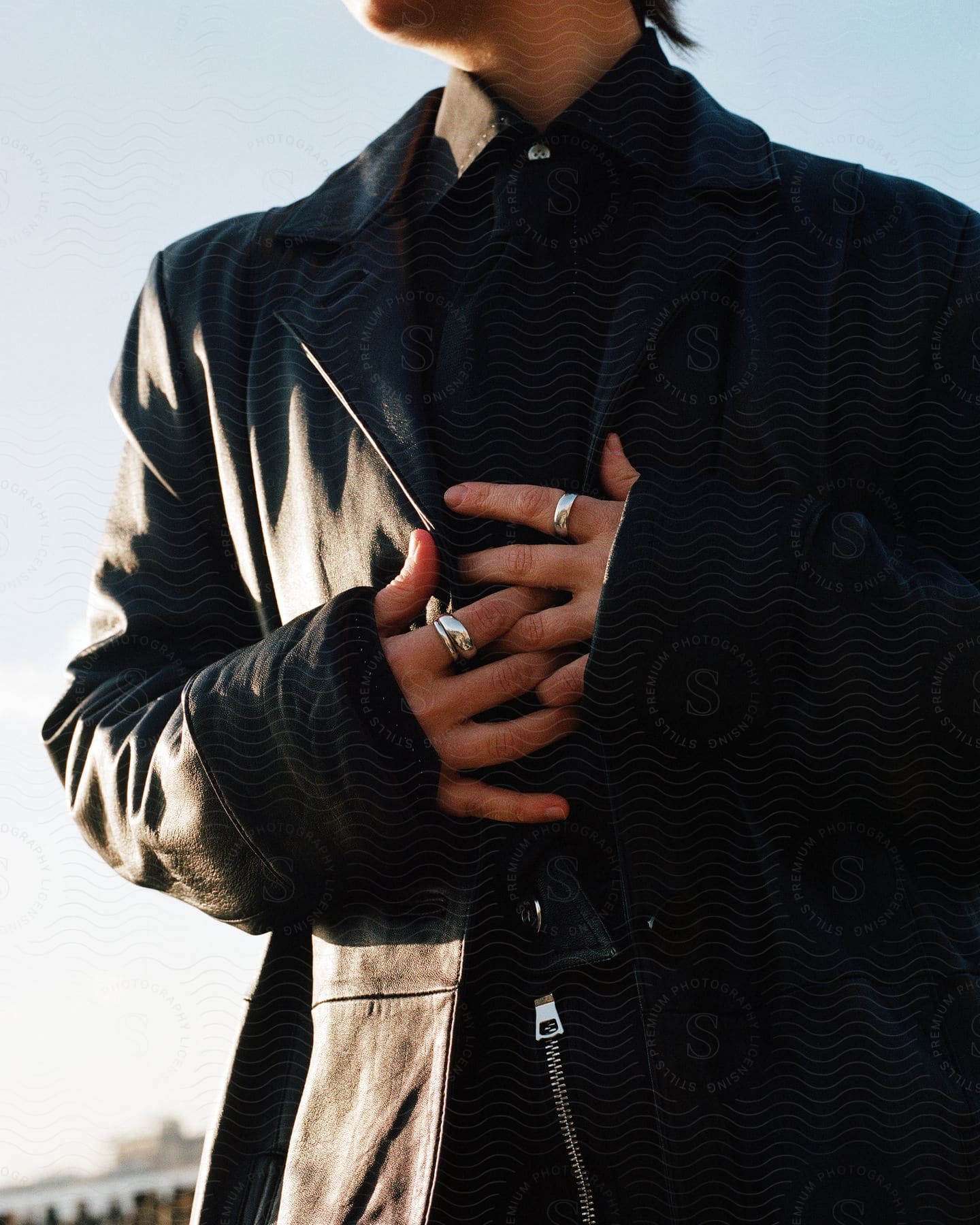 Man wearing black shirt and jacket hands on chest looking to the side