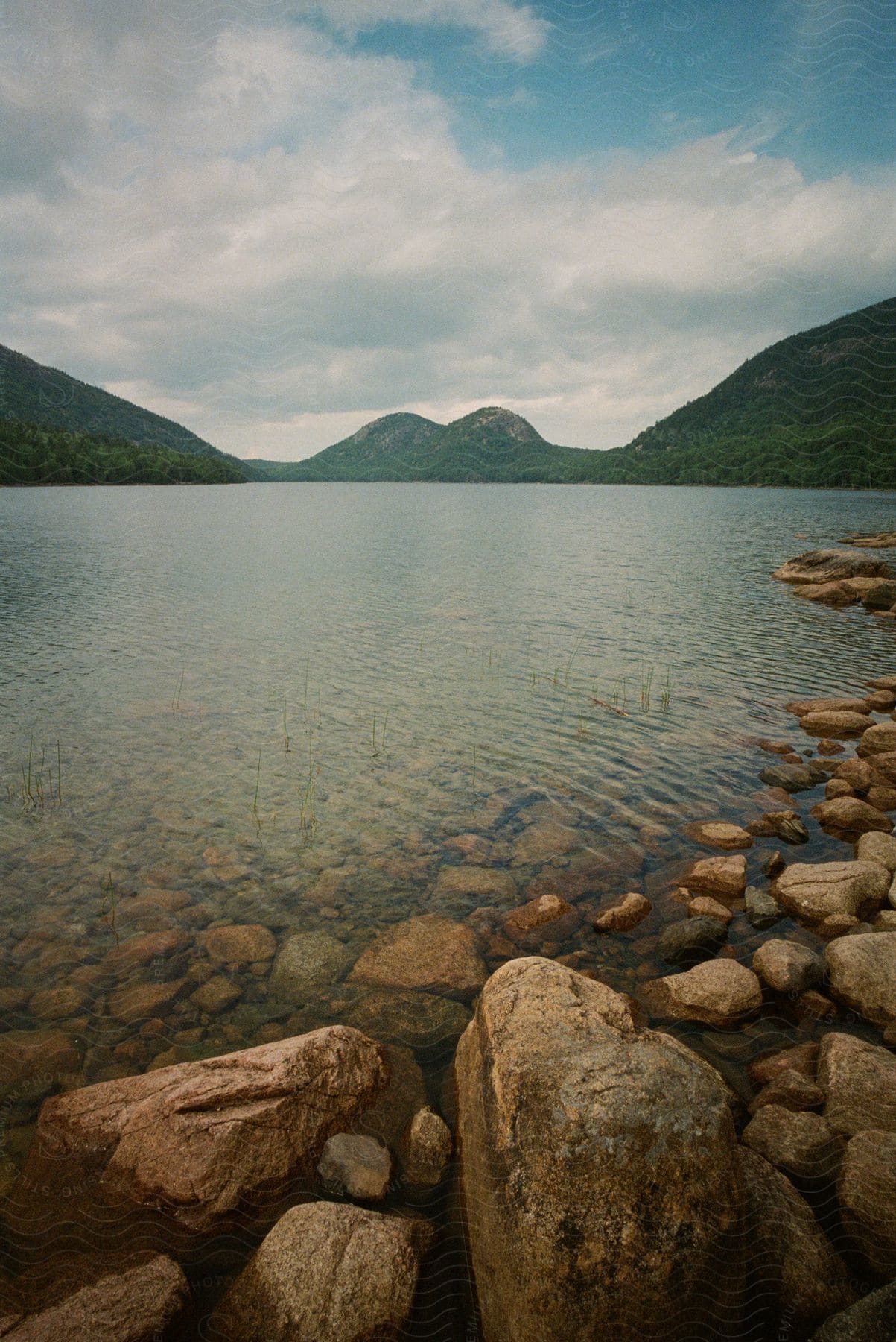 Rock bank of jordan pond north and south bubbles mountains across the pond in acadia