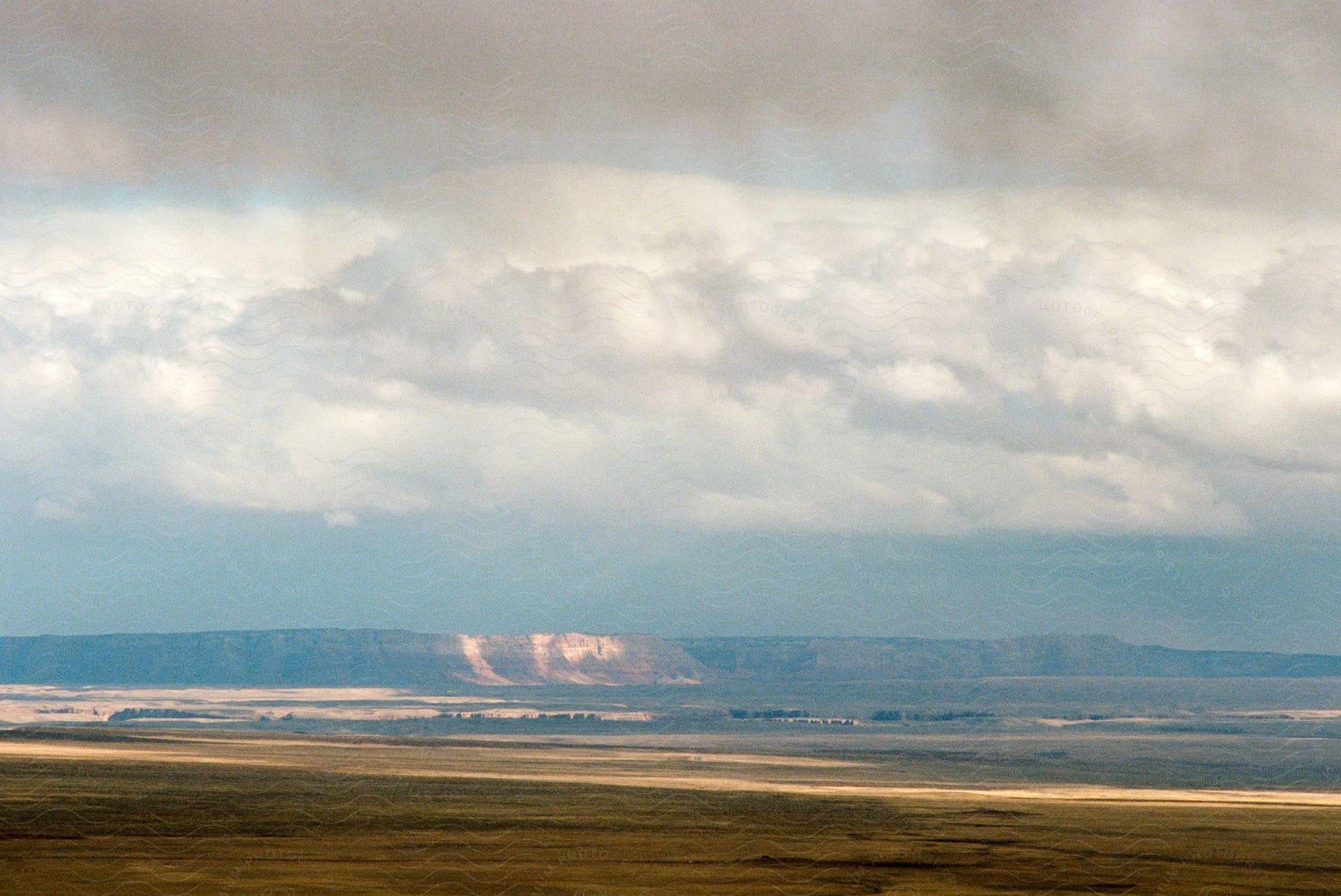 Grassland with distant mountains and thick white clouds in south west usa