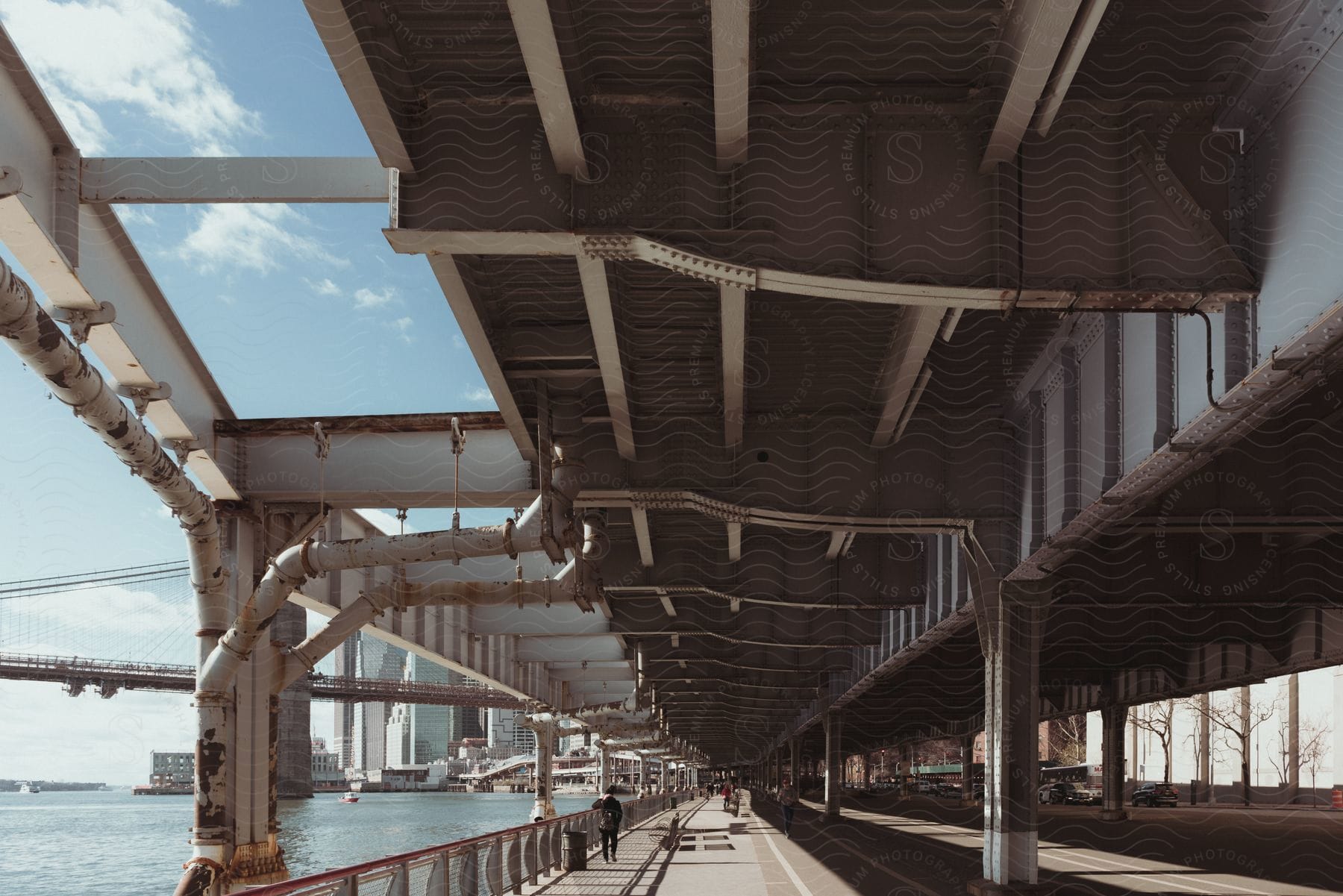 People walking under a bridge in a large city