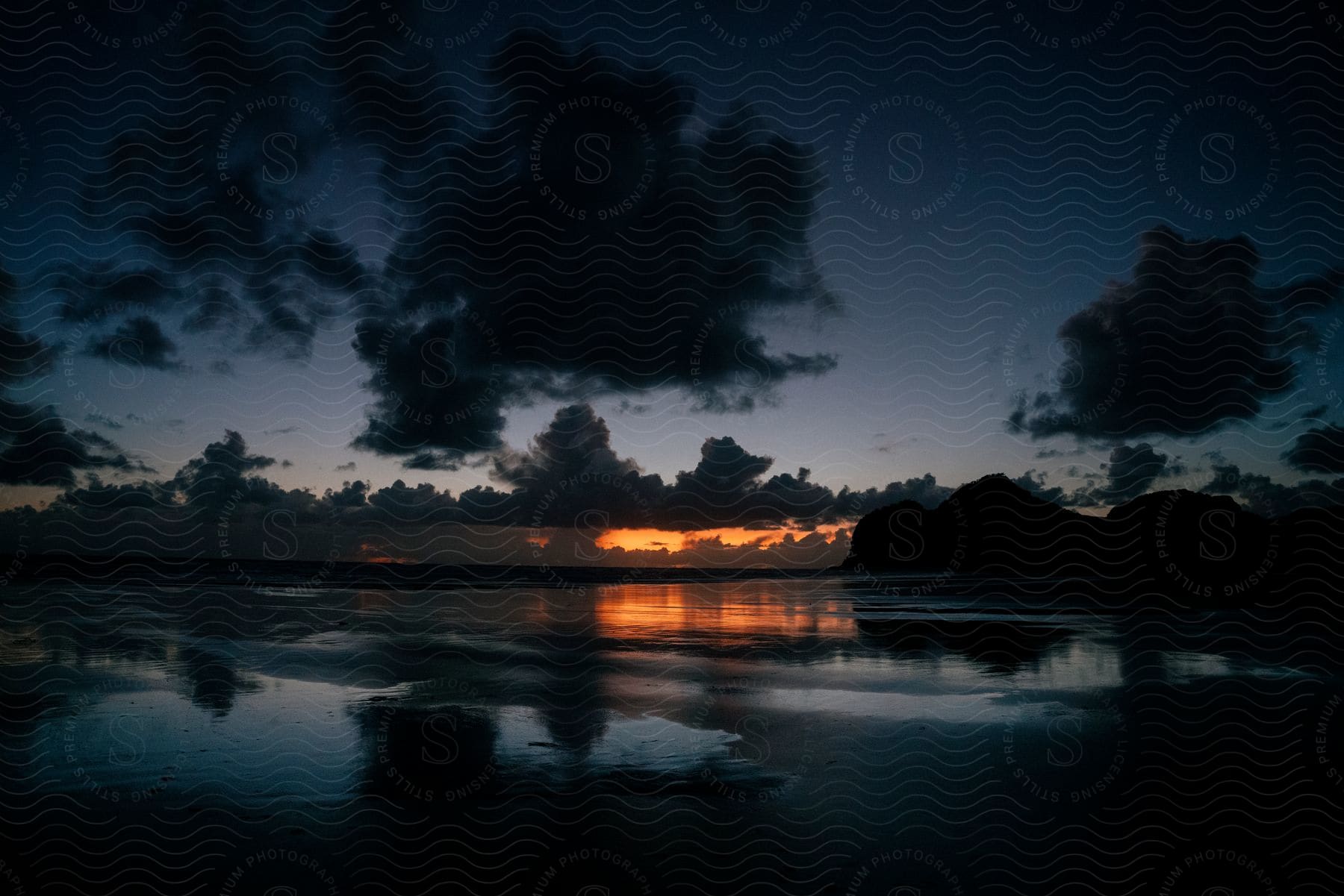 A landscape of the ocean and sunset at dusk on the shoreline