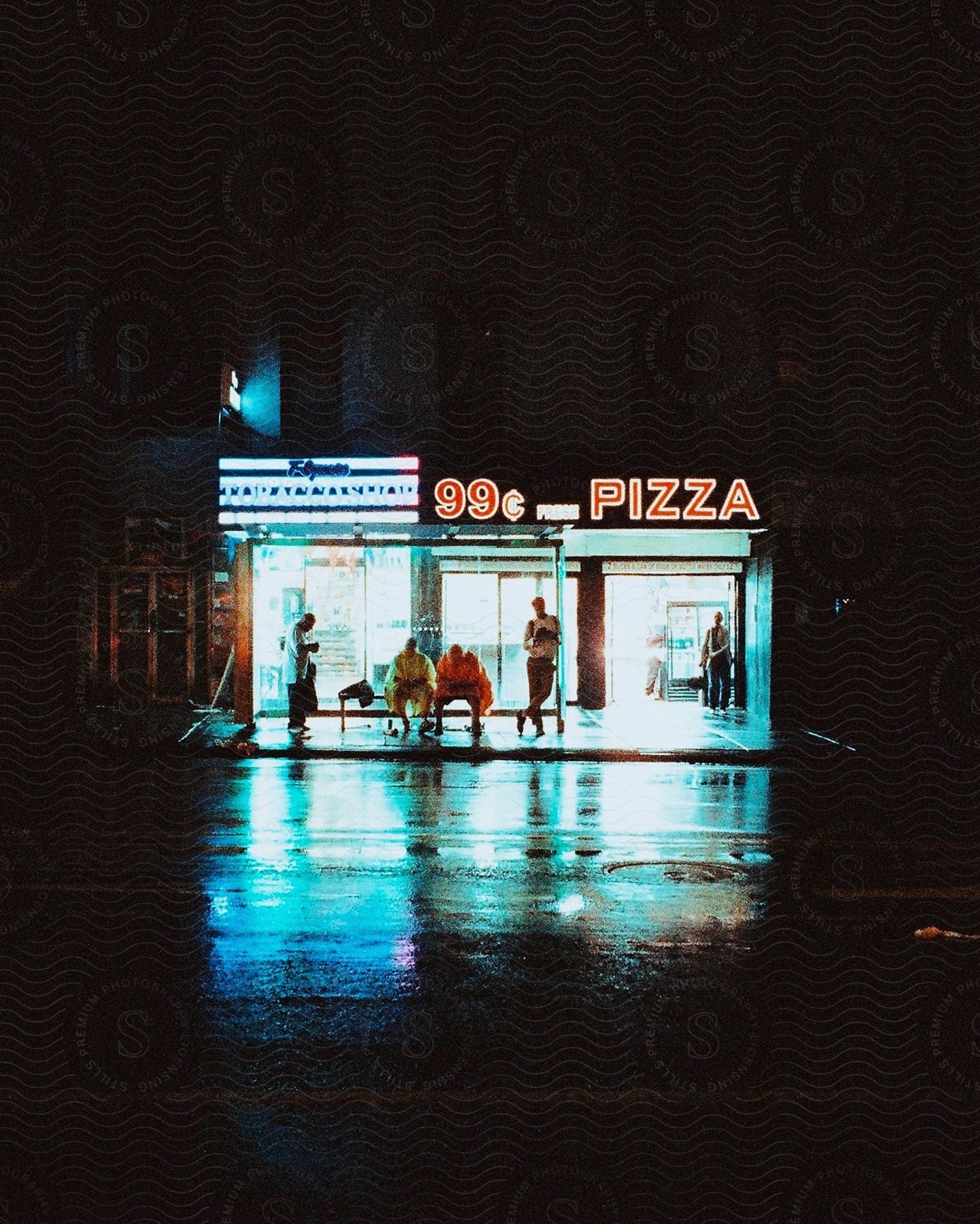 People gathered in front of a lit pizza shop at night