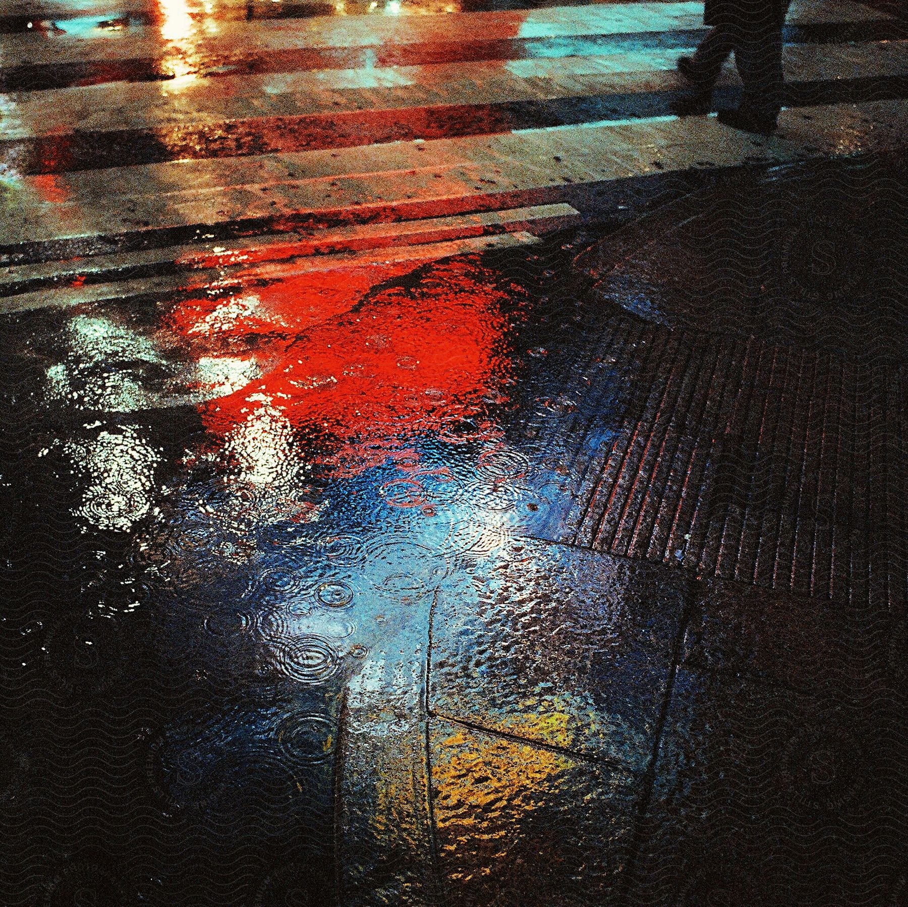 City lights reflecting on wet ground from rain in an exterior setting at night time