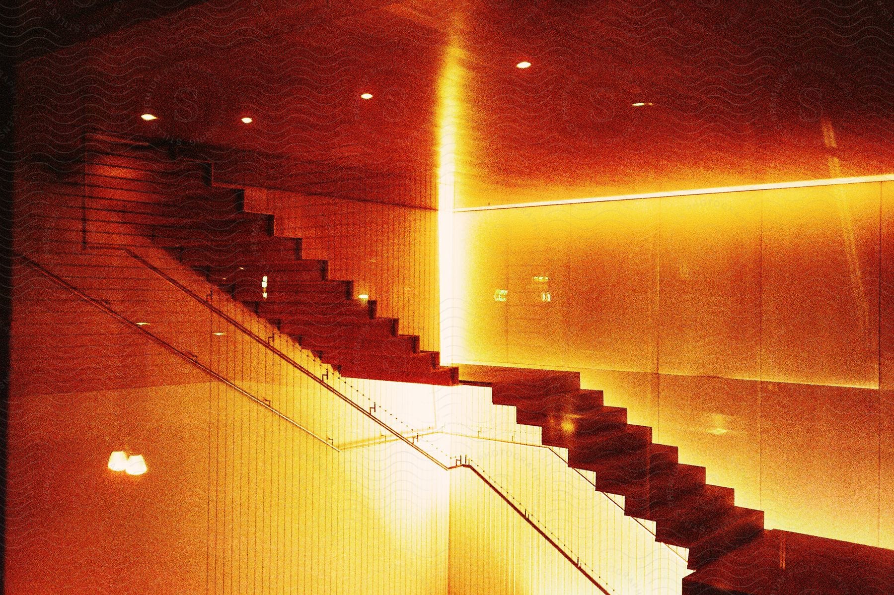 Indoors staircases under intense orange lights in an architecture setting