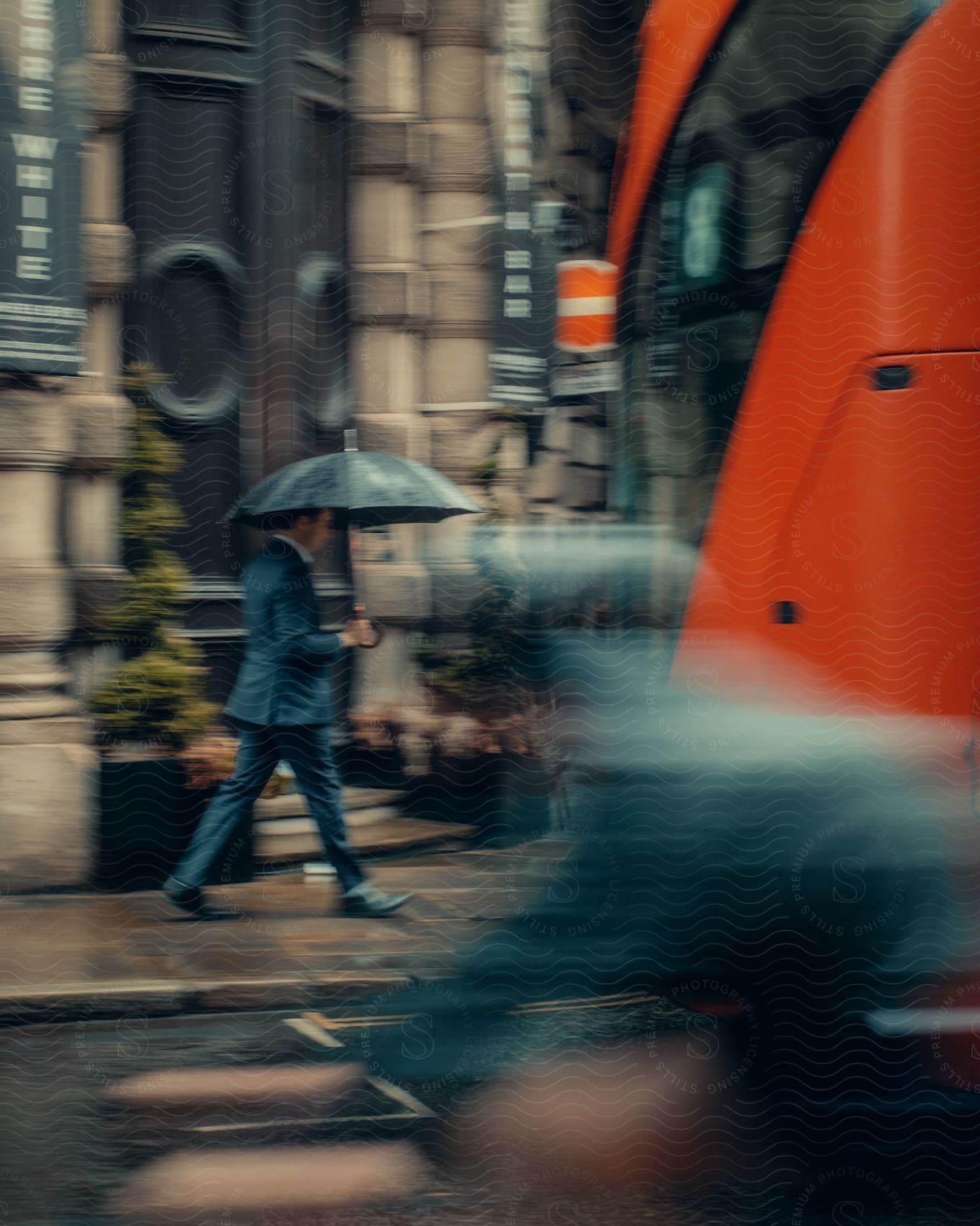 A man walking outdoors in downtown london while holding an umbrella