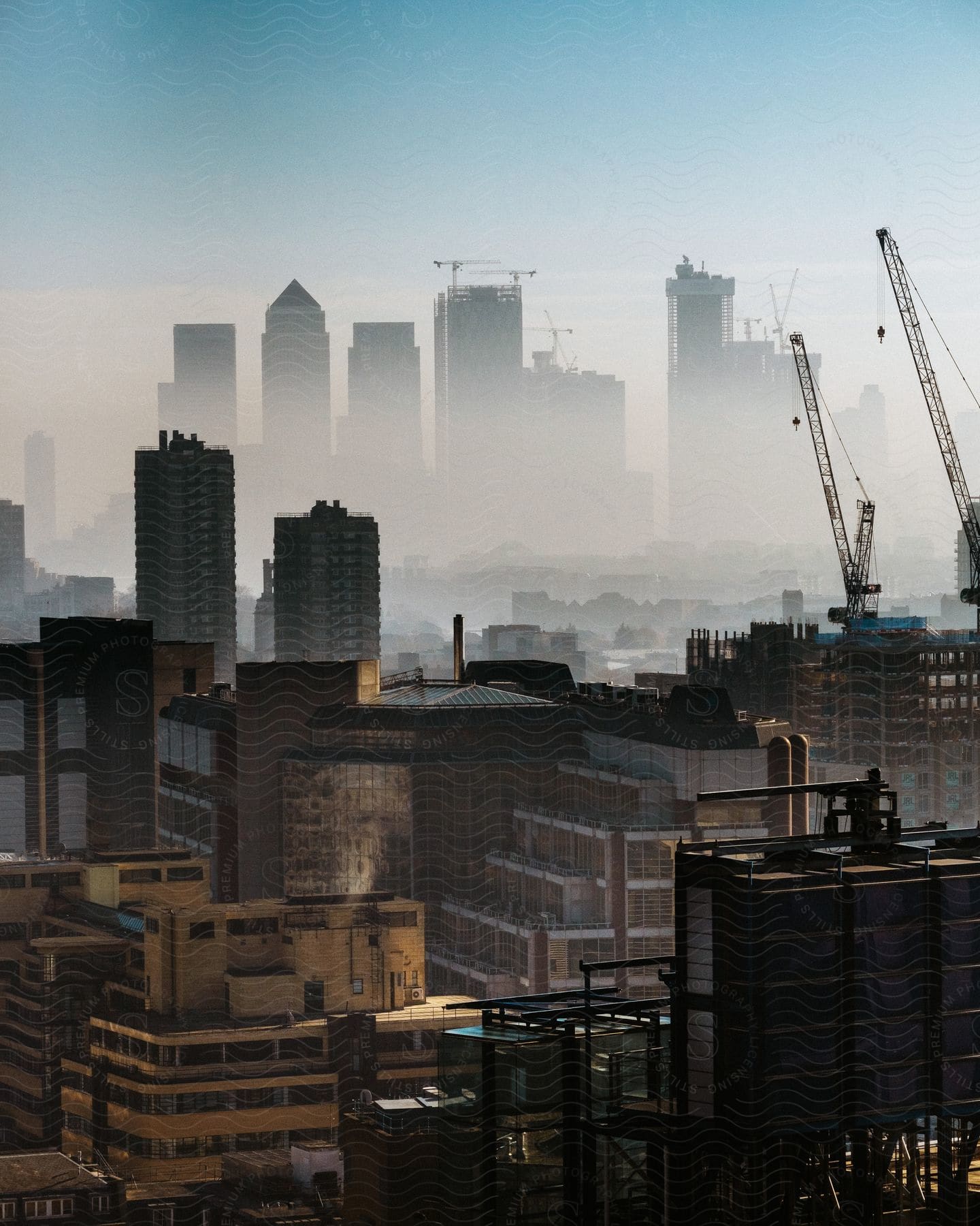 Construction site with cranes and distant skyline in fog in the city