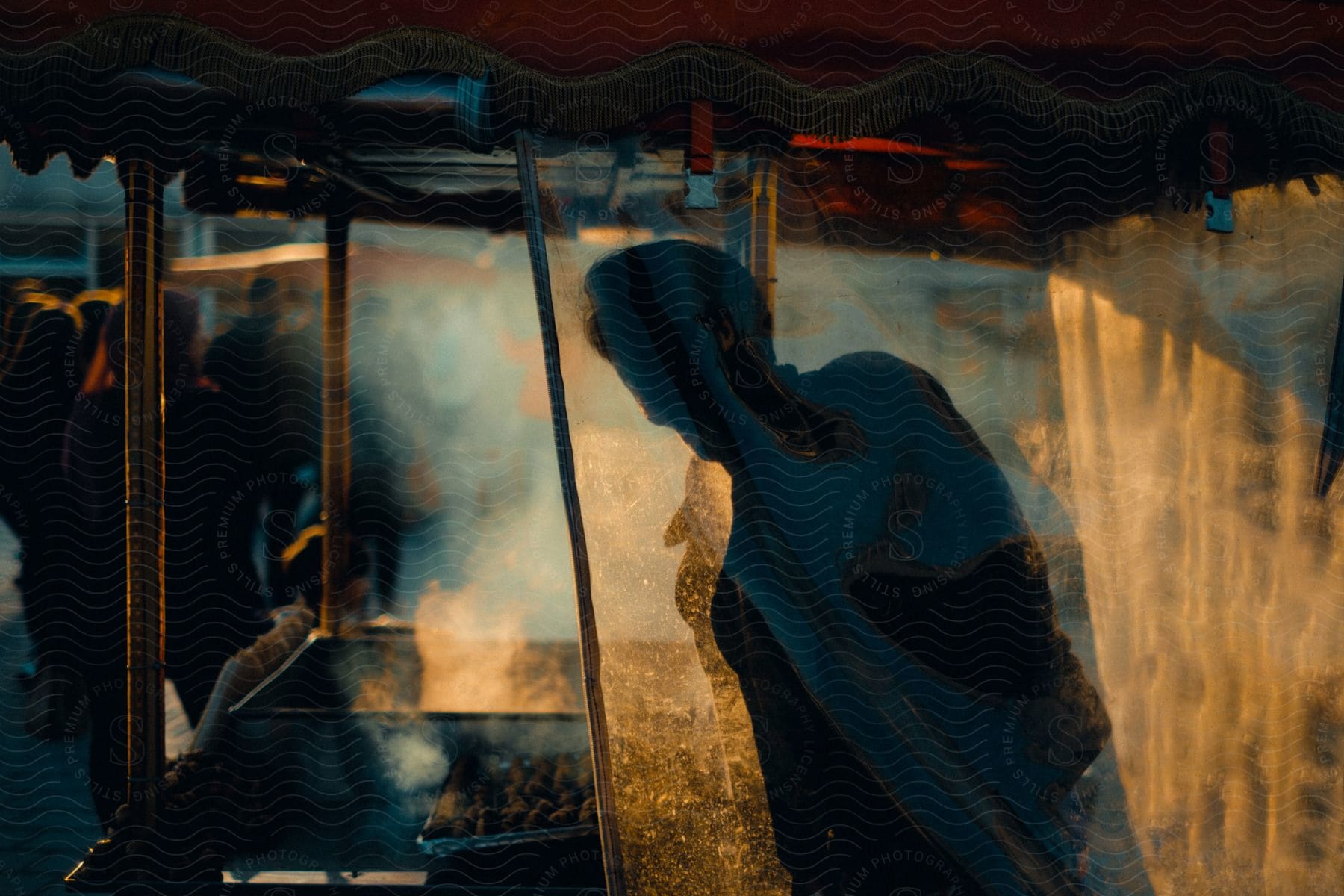 A silhouette of a food stall is seen against the sunlight on a city street