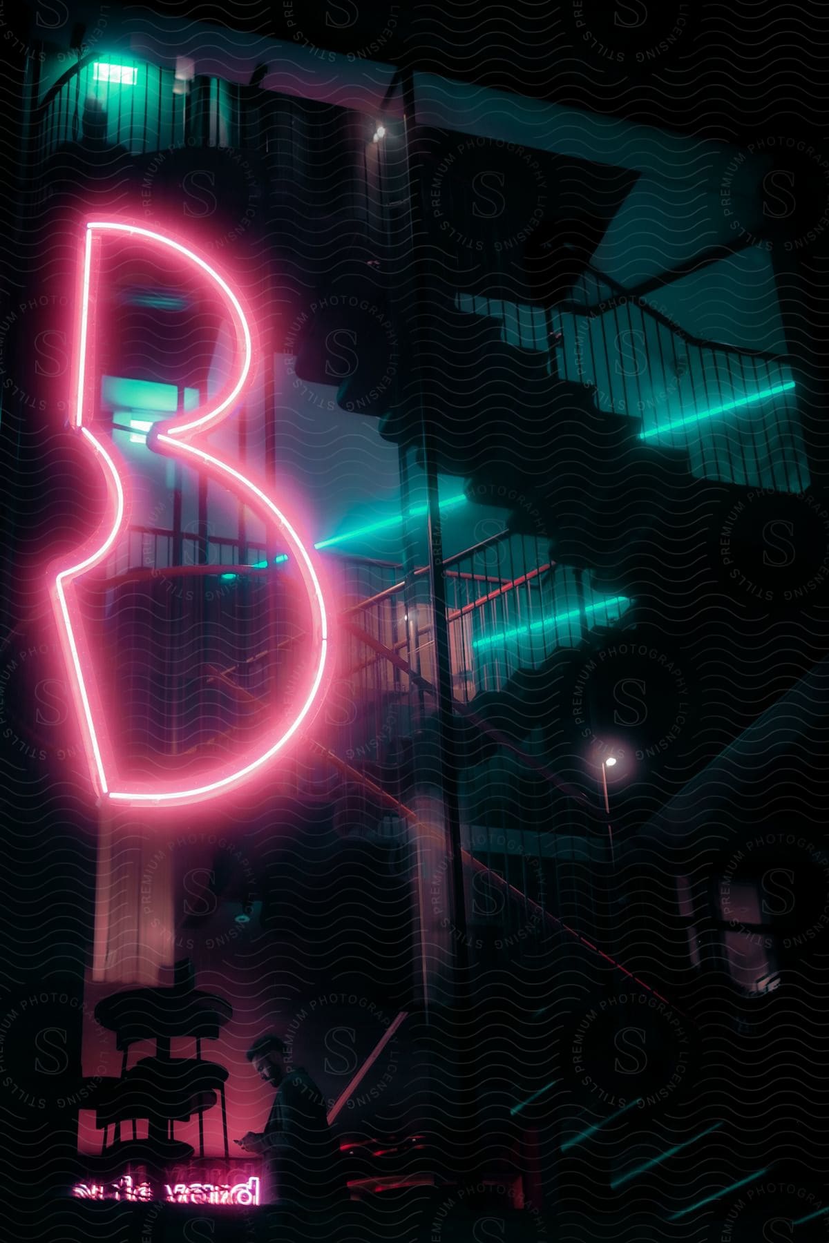 A neon b shaped sign hangs in front of an outdoor threelevel staircase of a building in london