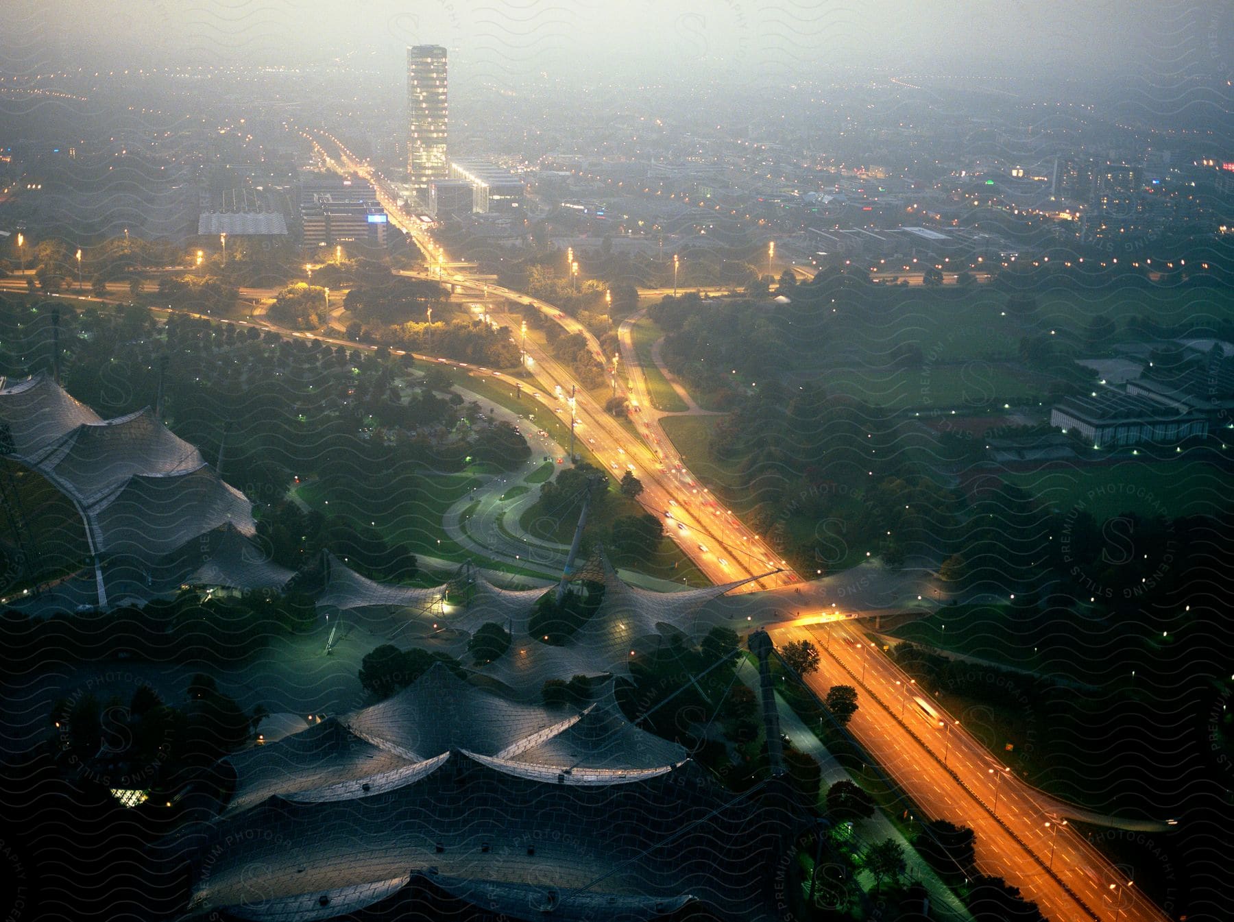 Aerial cityscape at night with illuminated buildings tower blocks and highway