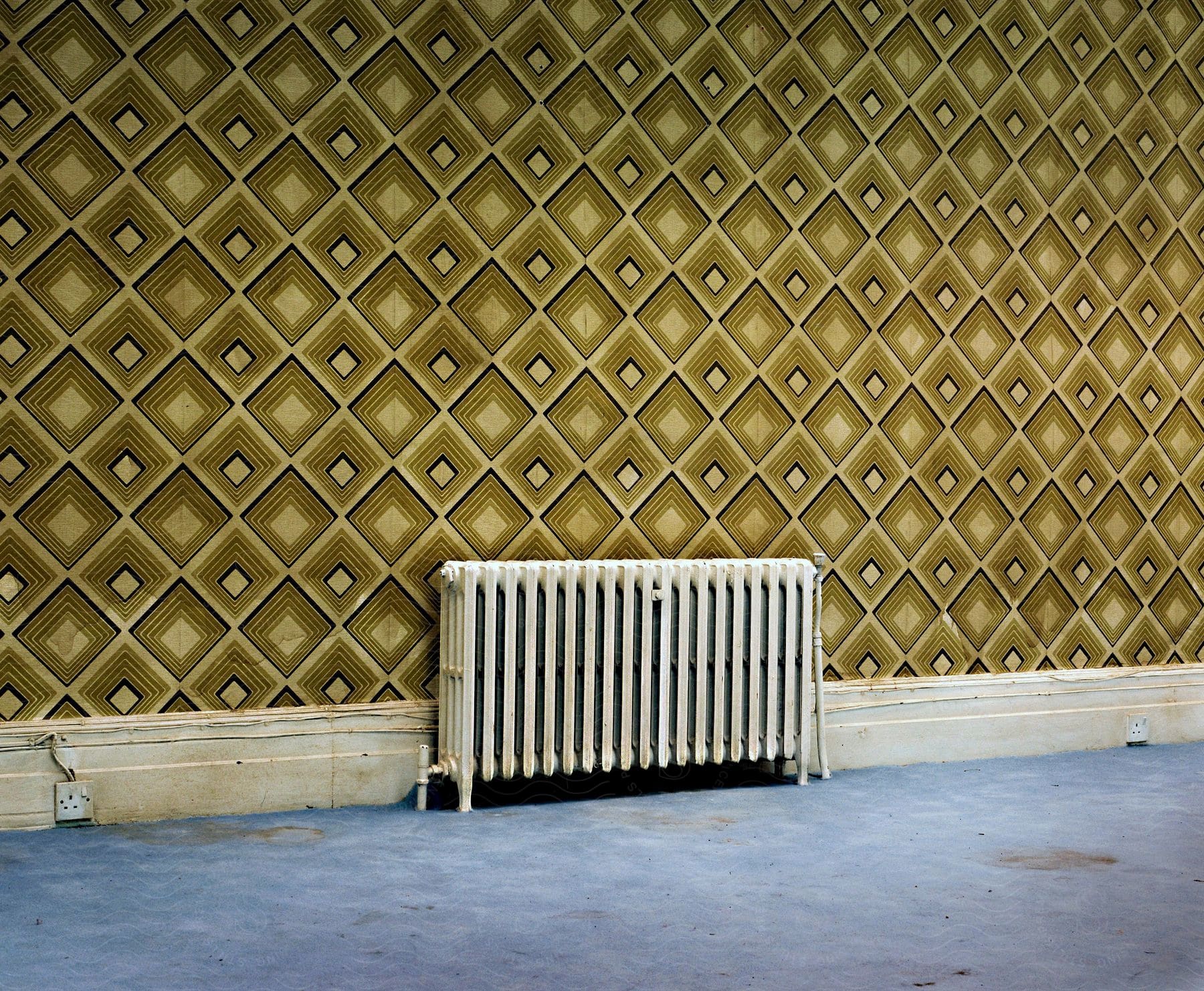 Wall with heater and wallpaper with triangular shapes in an interior space