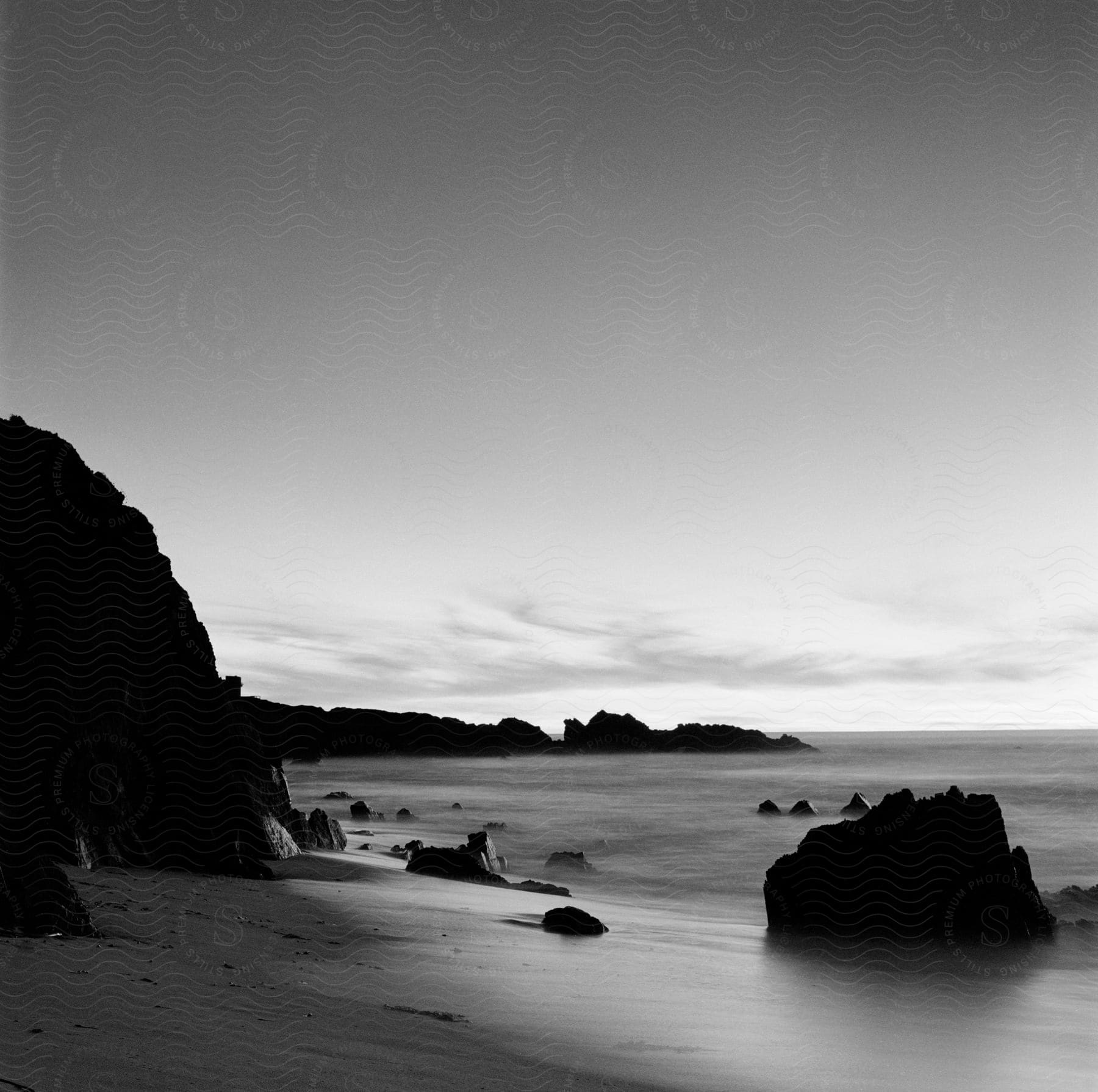 Waves roll in over the beach with rocks and rock formations along the coast under a cloudy sky at carmel beach california