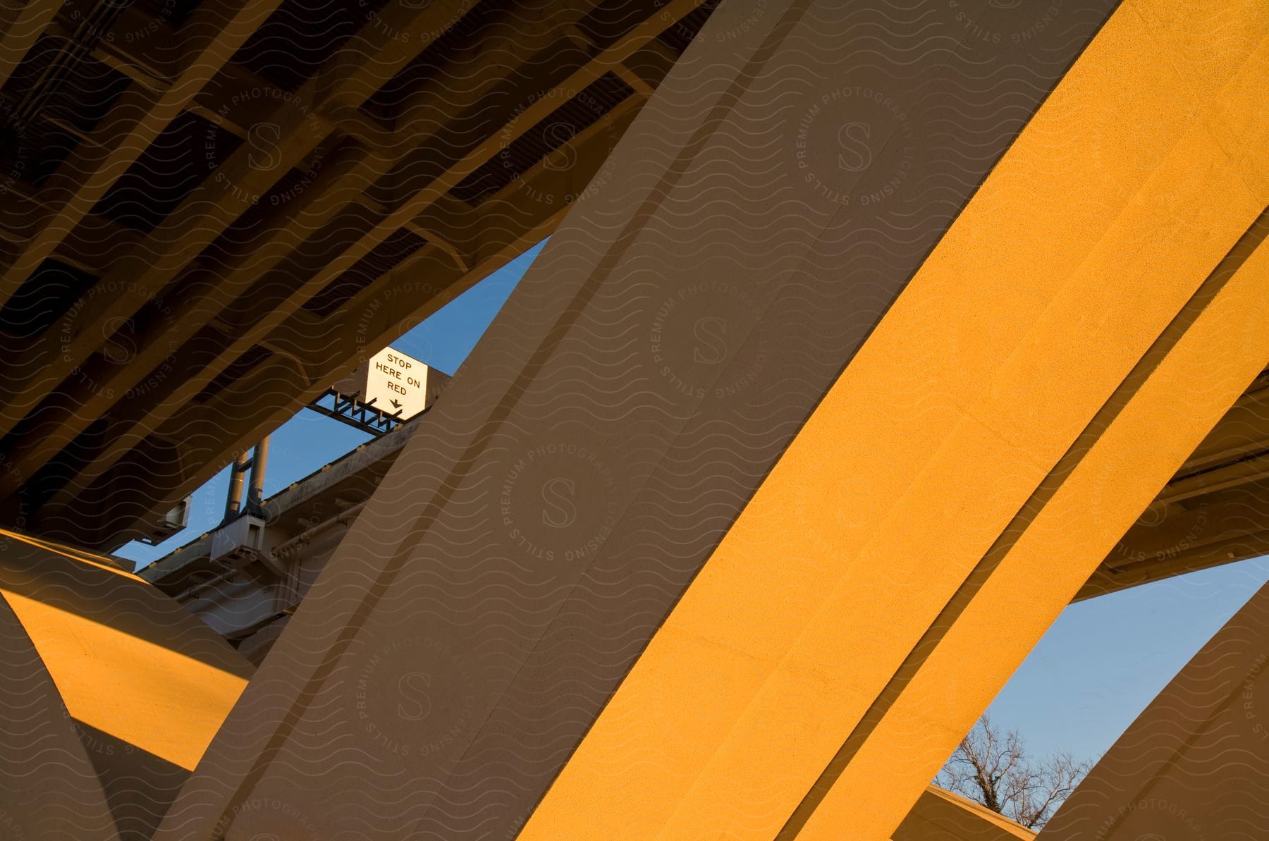 Bridge structure up close with a tiny street opening and billboard