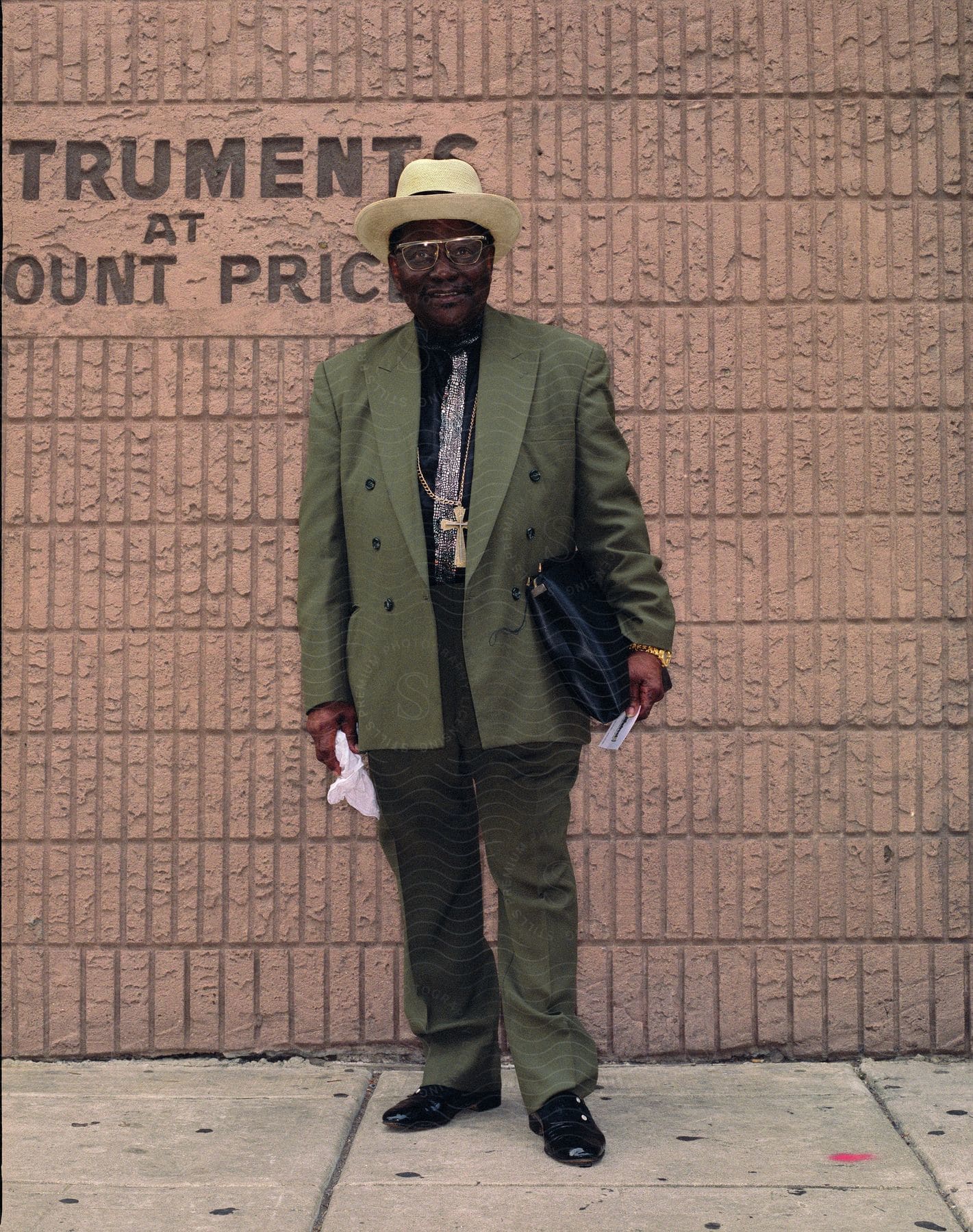 Smiling man poses with handbag in front of music instrument shop wall