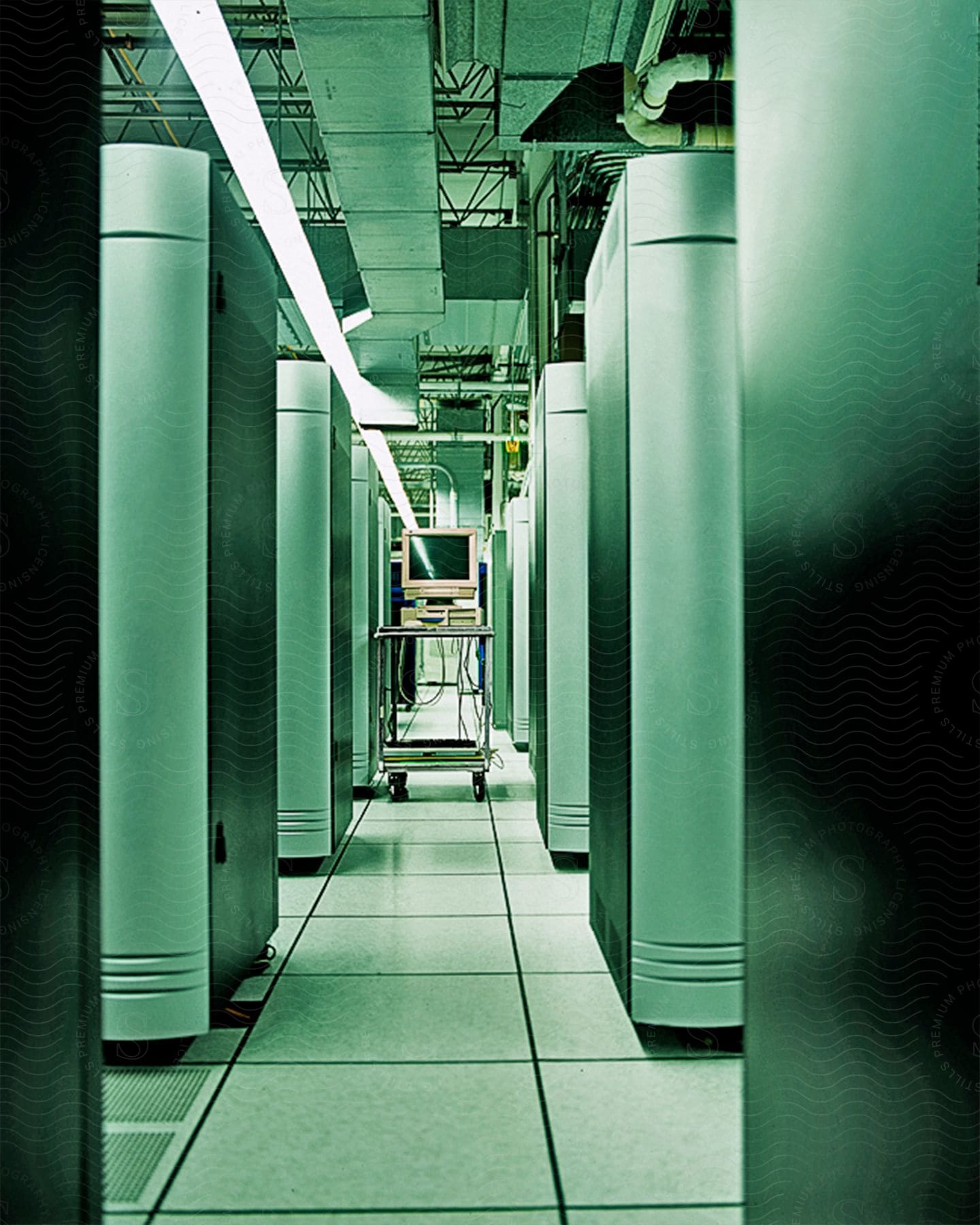 A room with a table in the middle of a path featuring computer equipment and wires