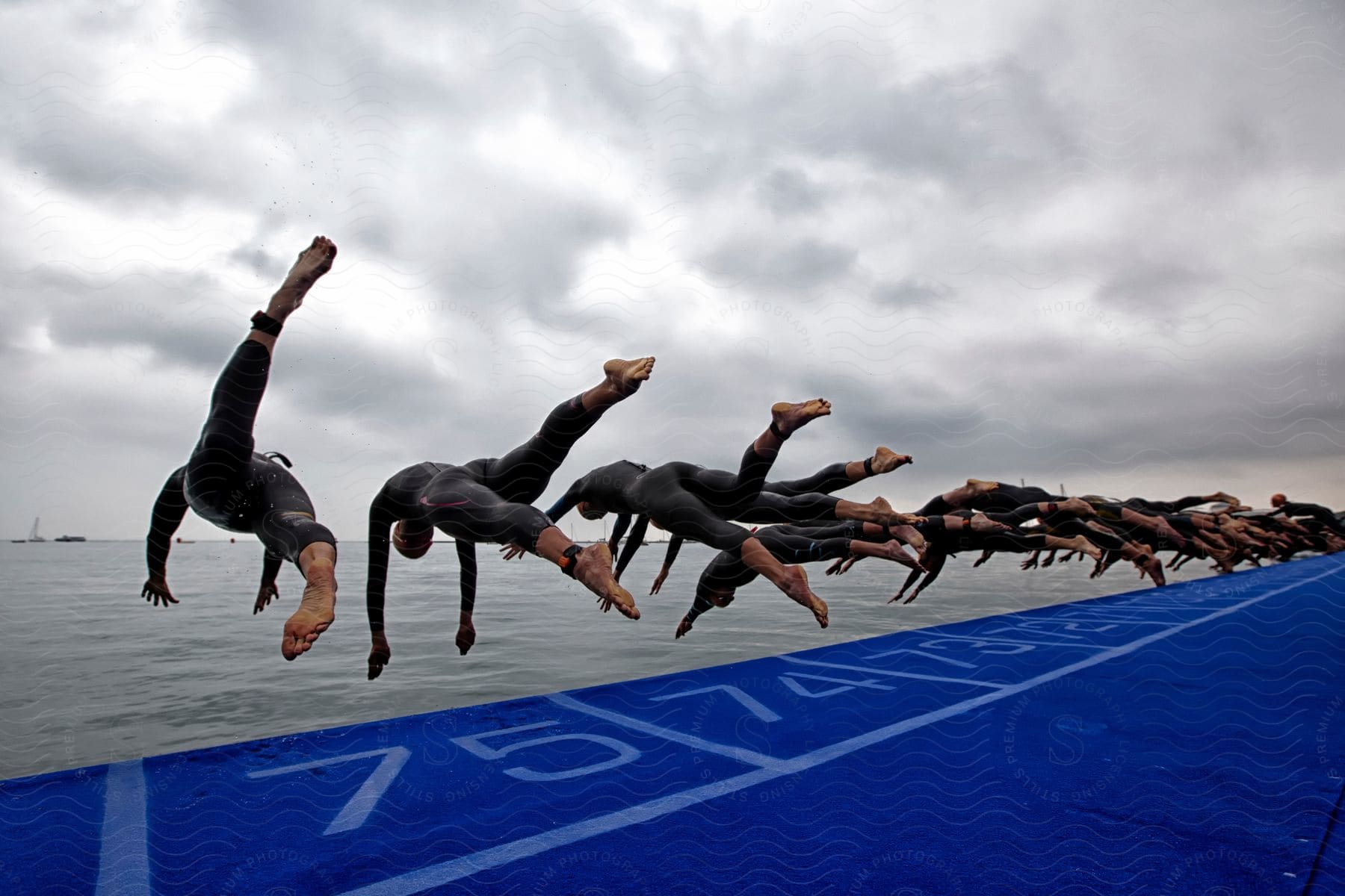 A group of people diving off a dock at daytime