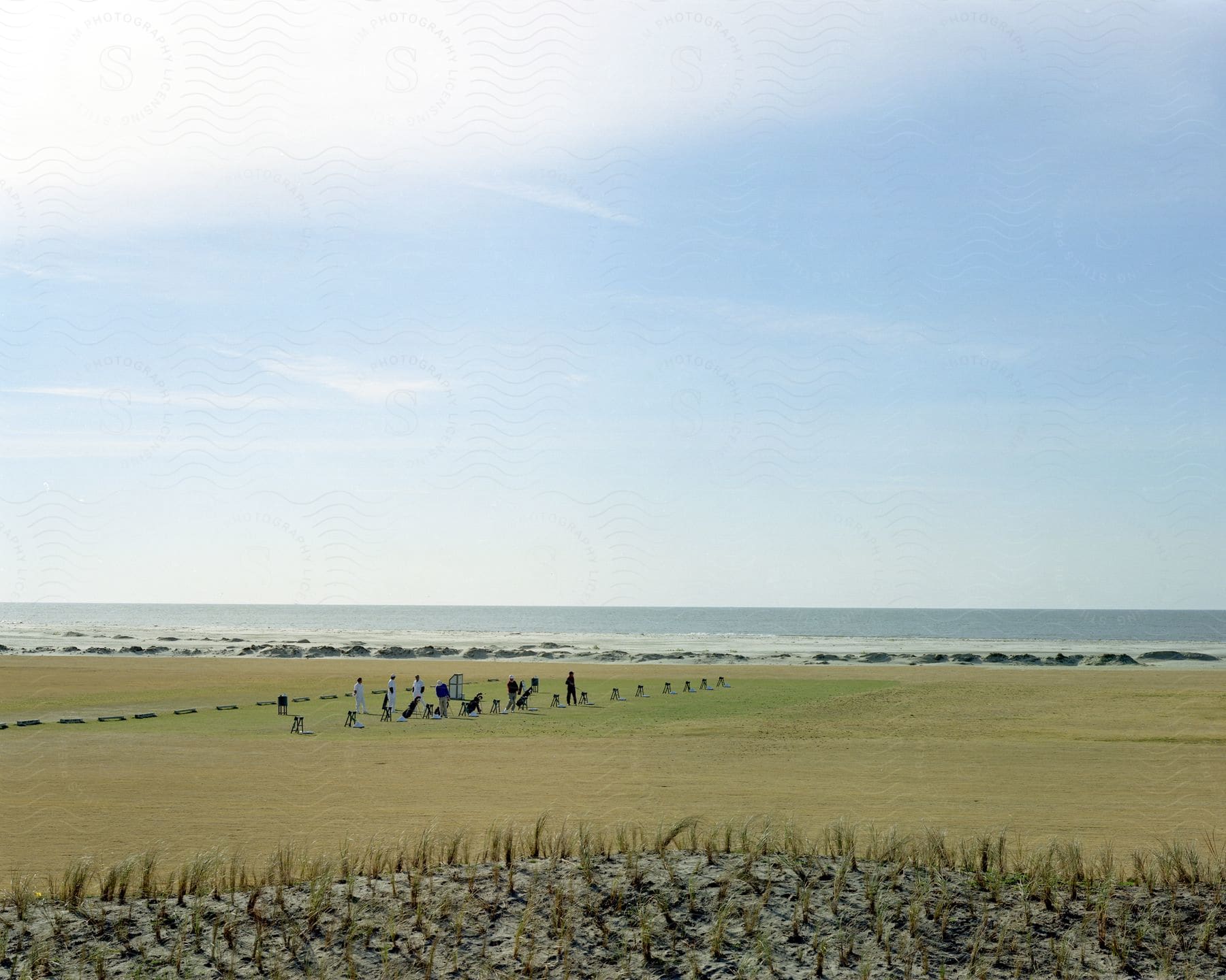 A wide field with clear clouds and people standing