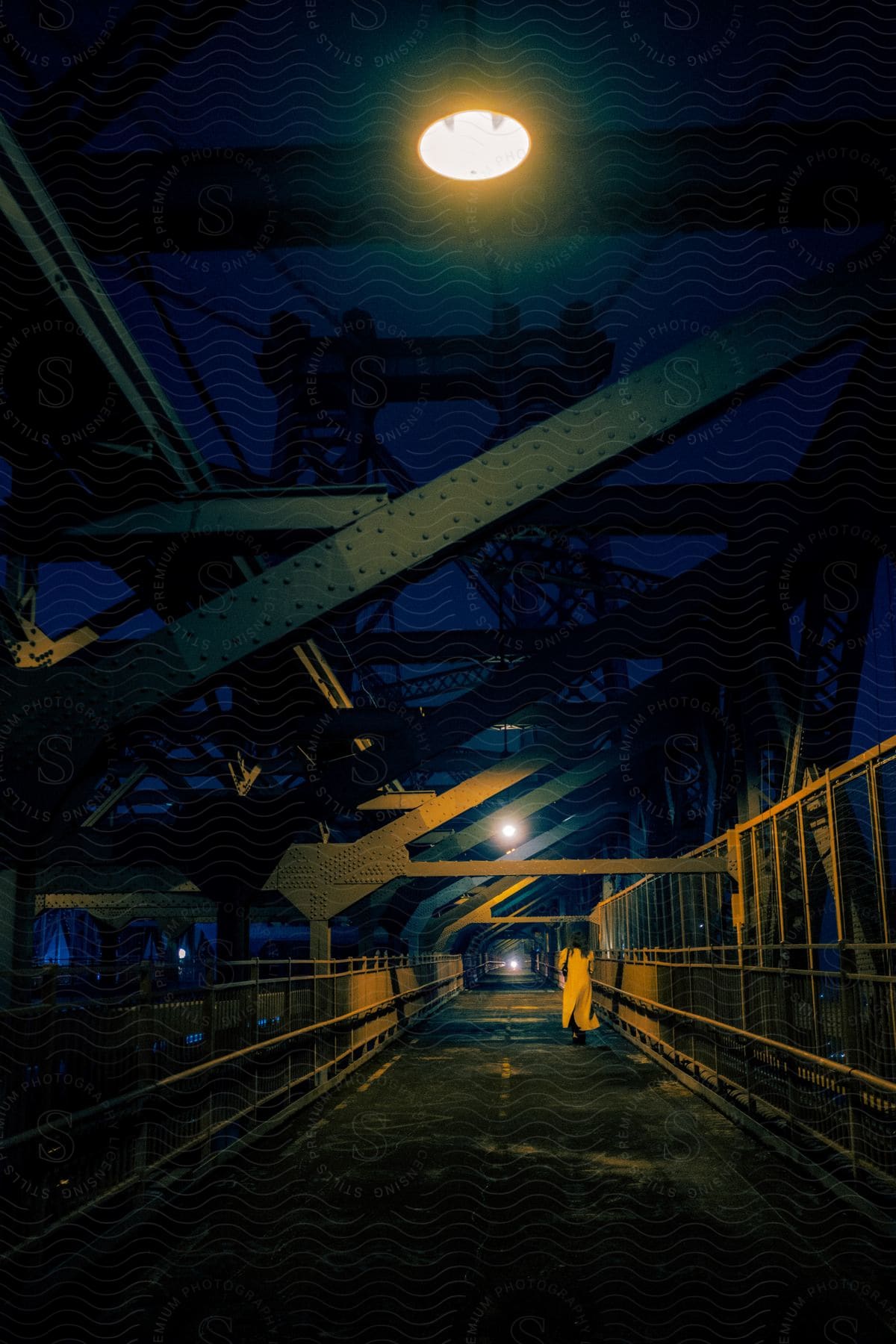 A figure dressed in white walks across a bridge under a starry night sky