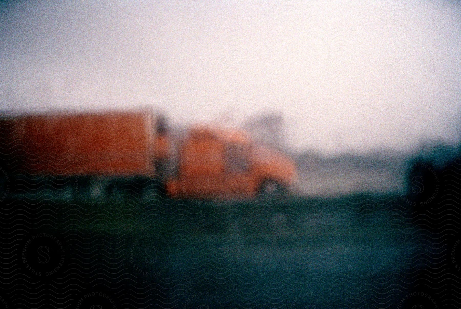 Blurry fish eye perspective of an orange shipping truck driving on the highway