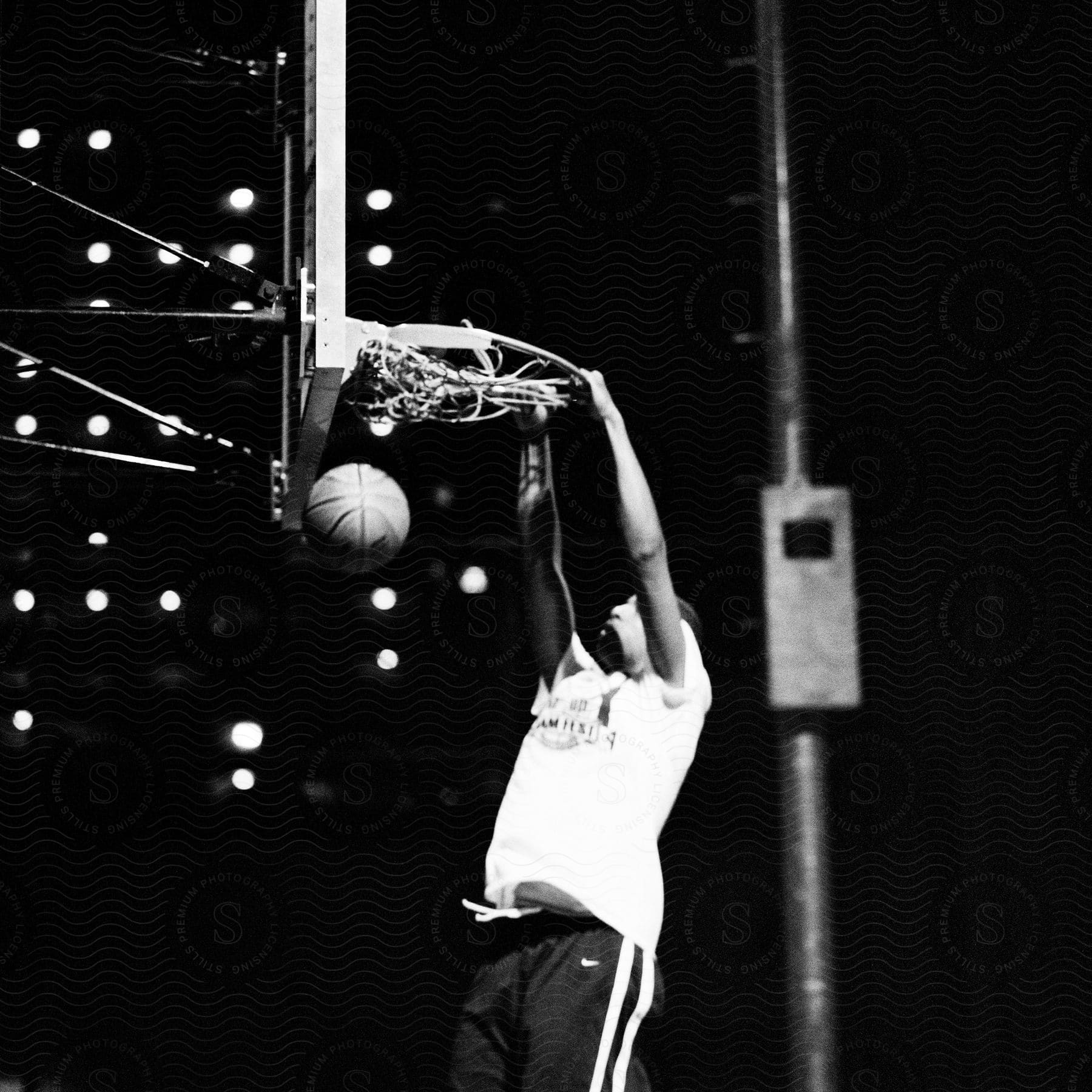 A basketball player shooting a layup and hanging from the hoop