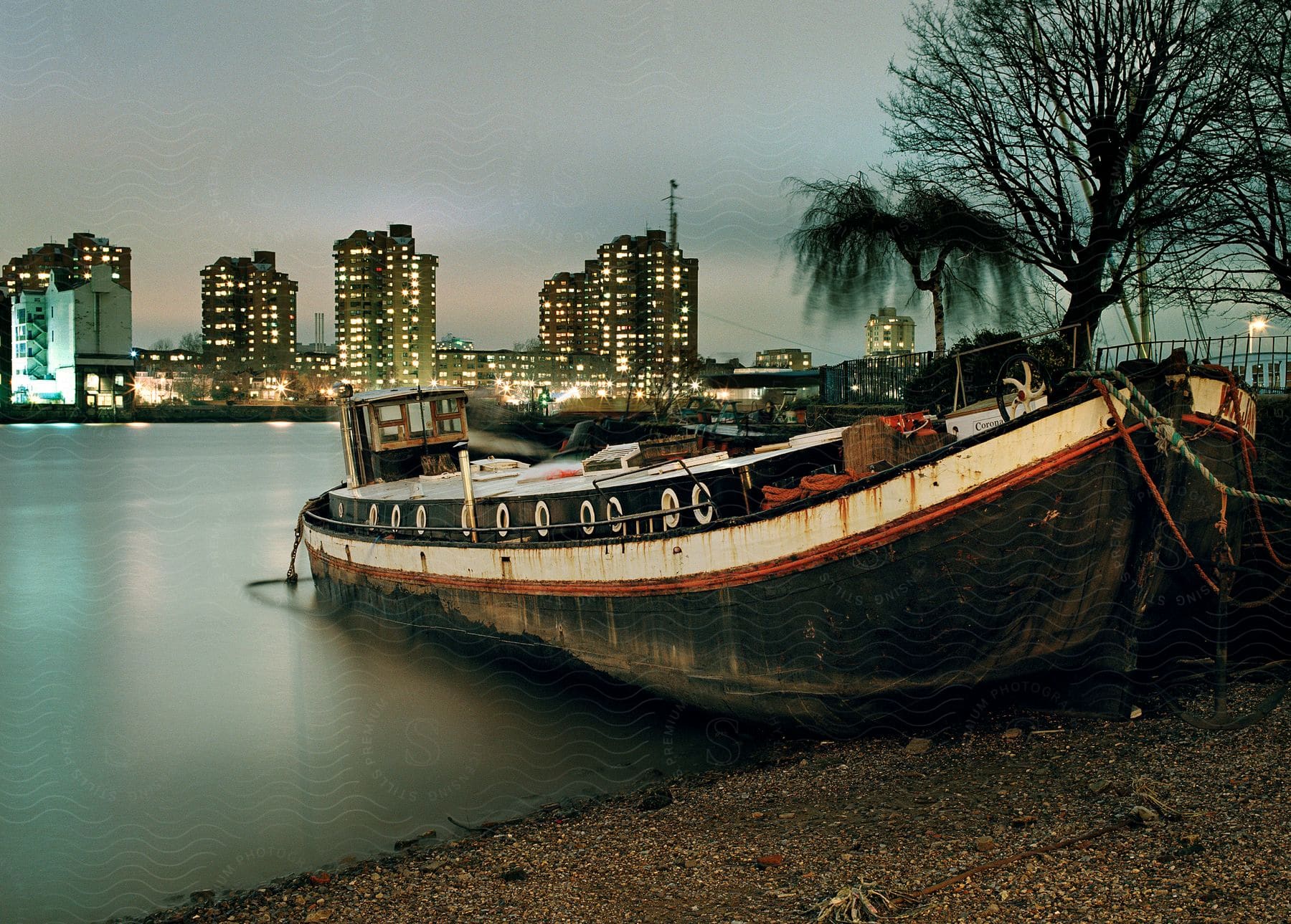 A decaying boat docked on a city shore