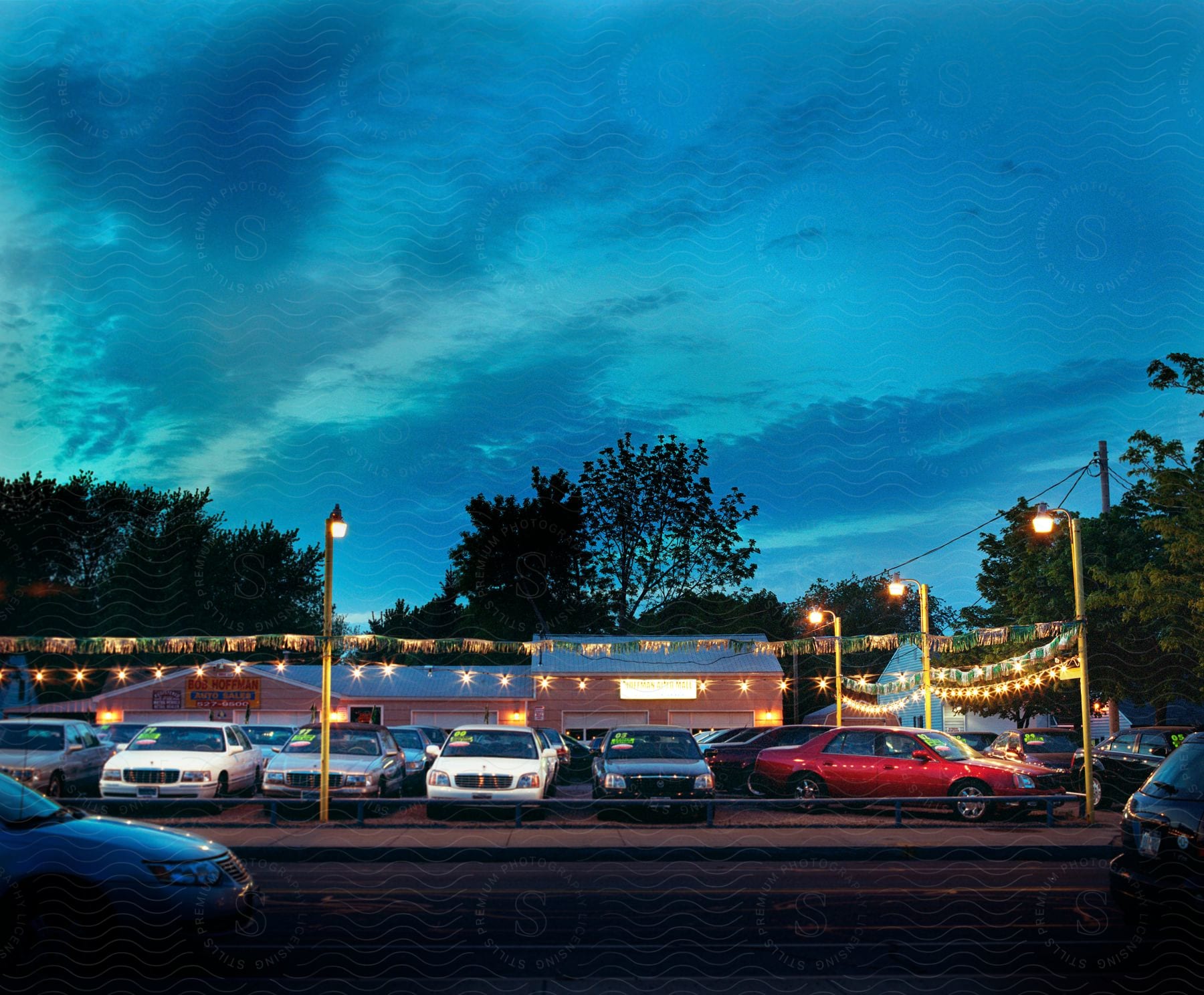 Exterior of car dealership with festoon lights lighting up the street at dusk