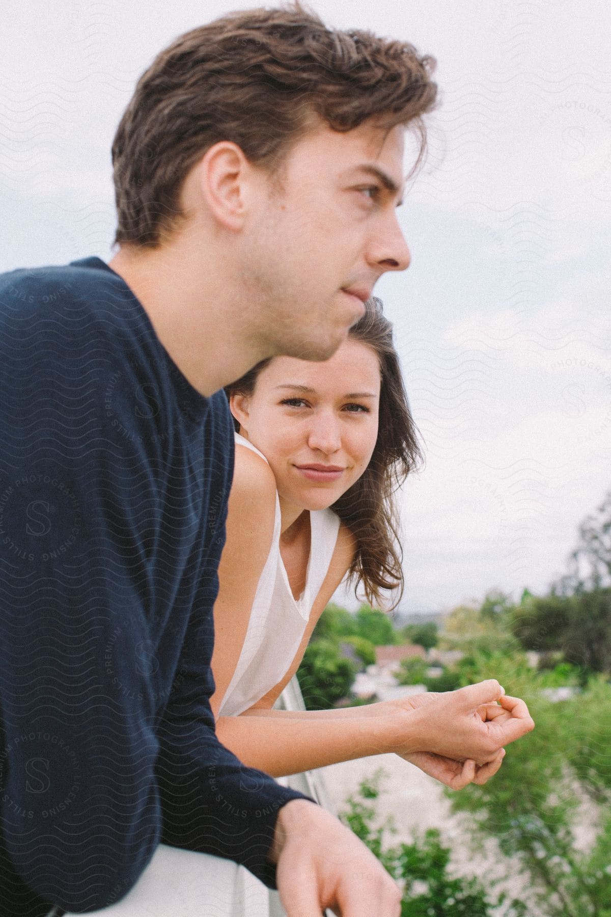 A man and a woman lean over a balcony engaged in conversation