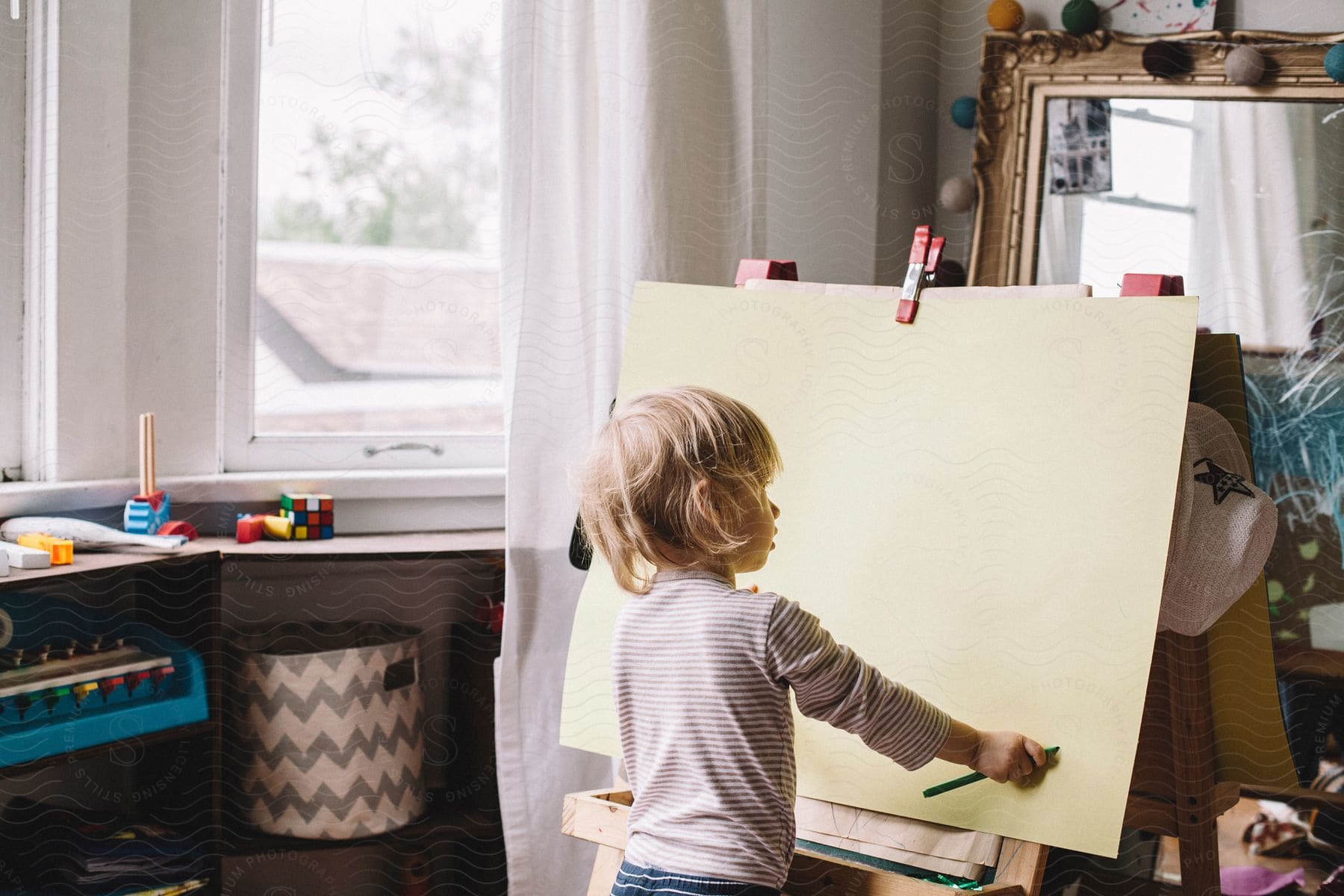 Small child standing in front of a blank easel ready to draw