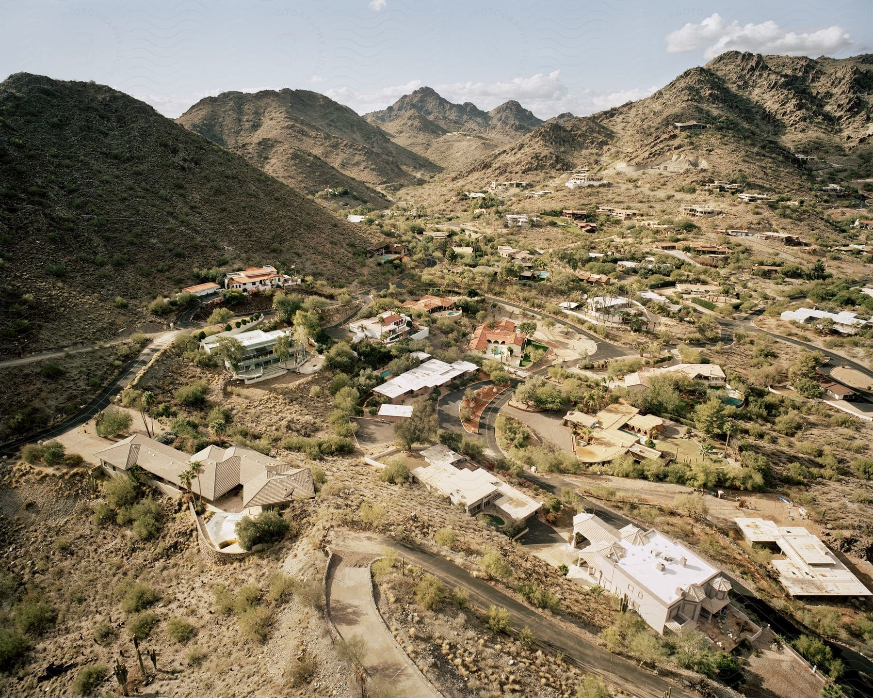 Aerial shot of a desert village surrounded by barren hills on a sunny day