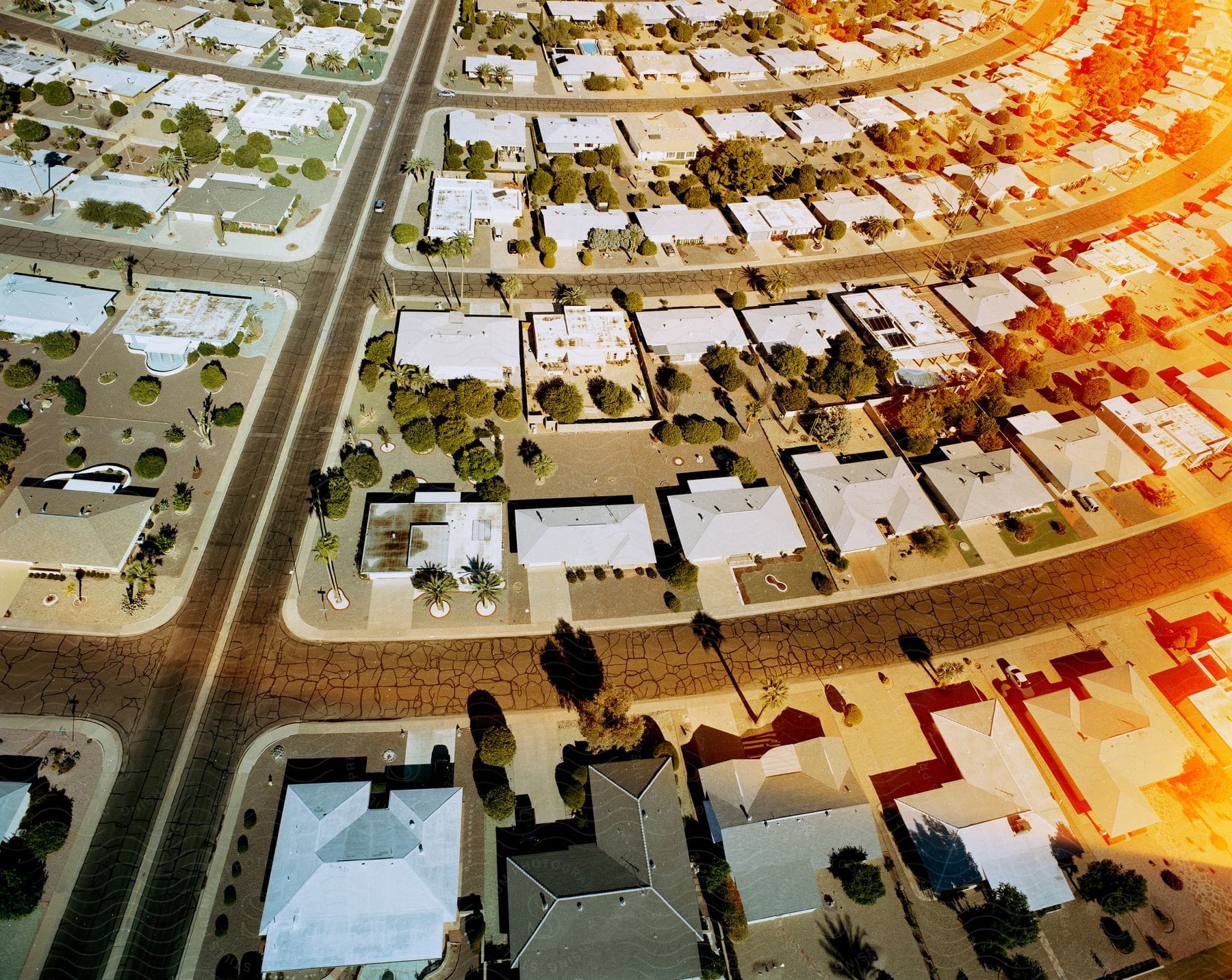 Cracked streets run through a neighborhood with white roofs