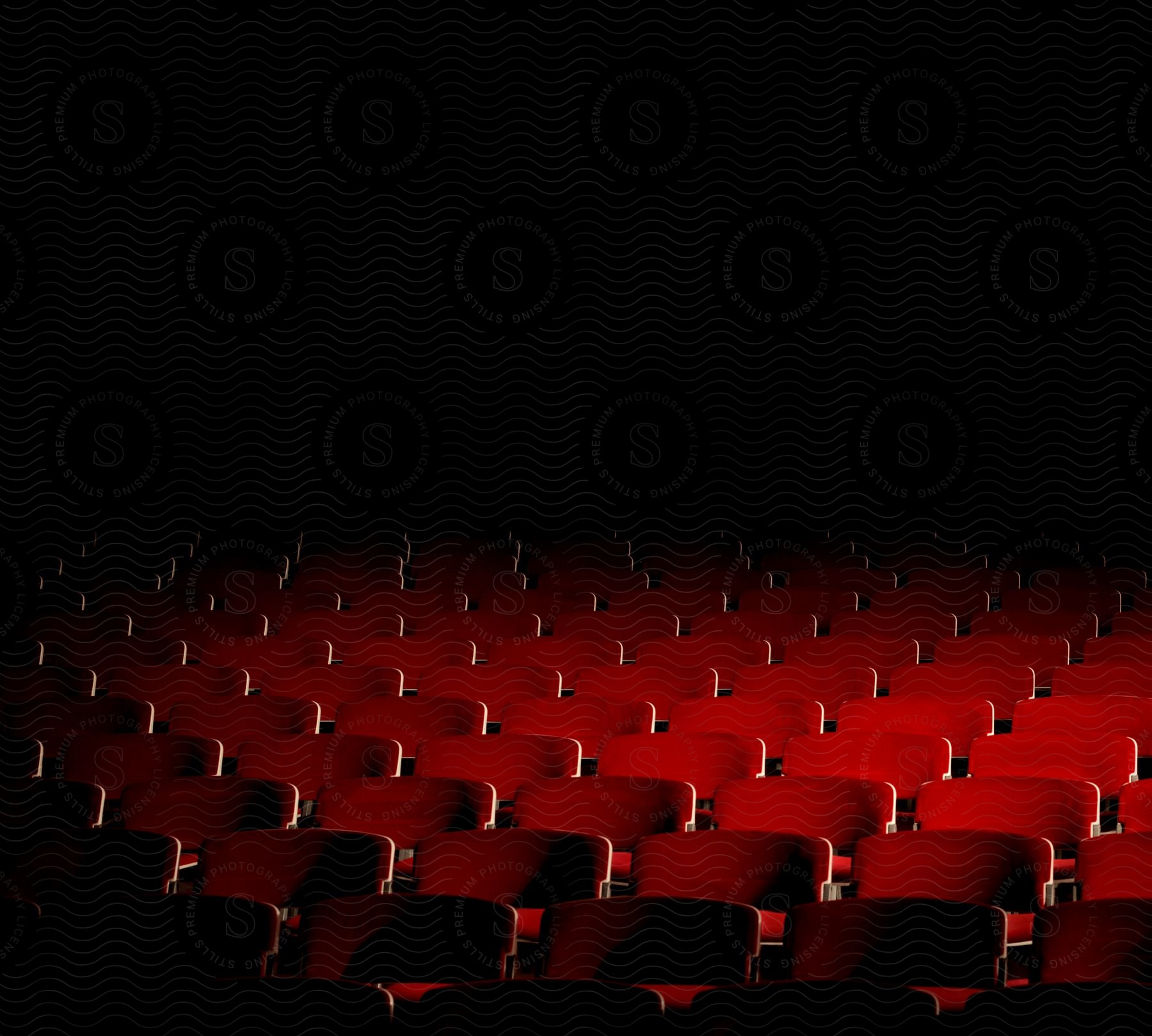 Red chairs arranged in rows in a dimly lit lecture hall