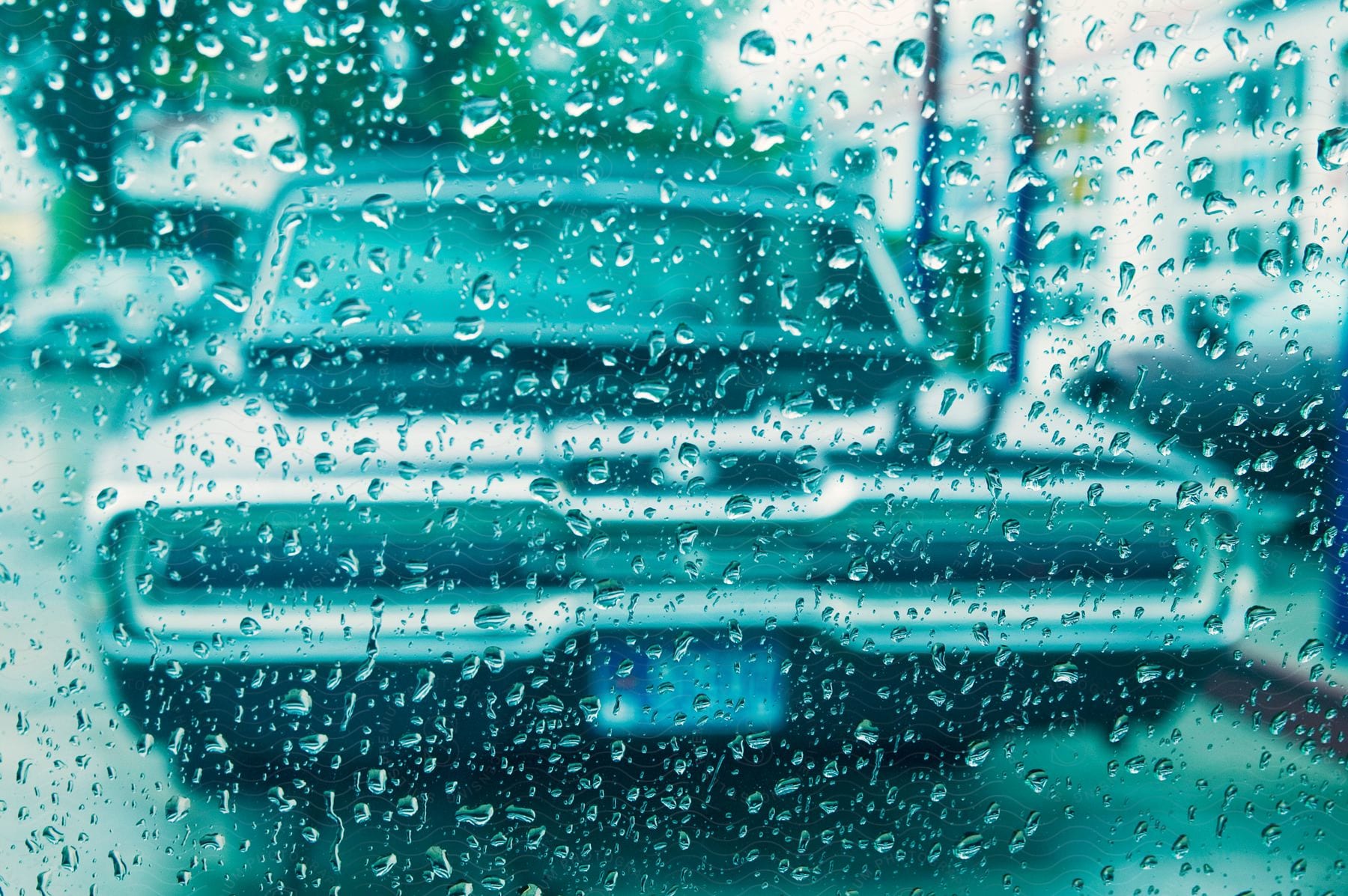 An old car seen through a watersplashed glass