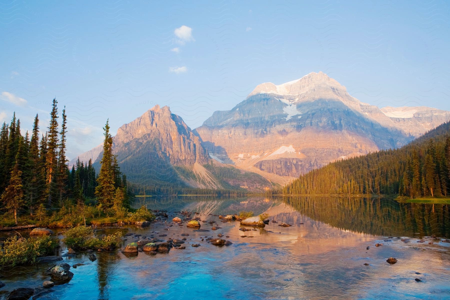 A lake with a forested bank and mountains in the background