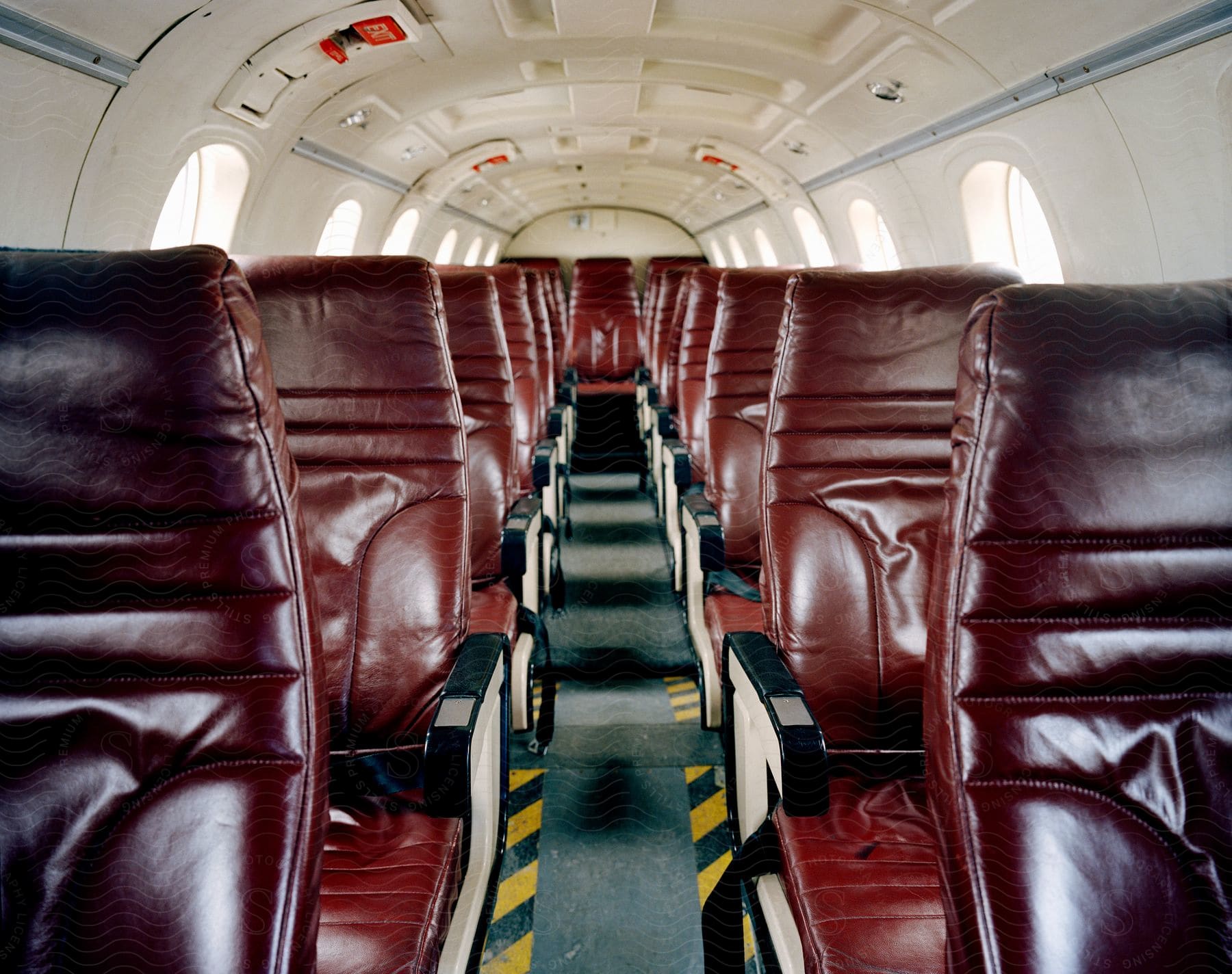 Empty brown leather seats in an airplane aisle during the day