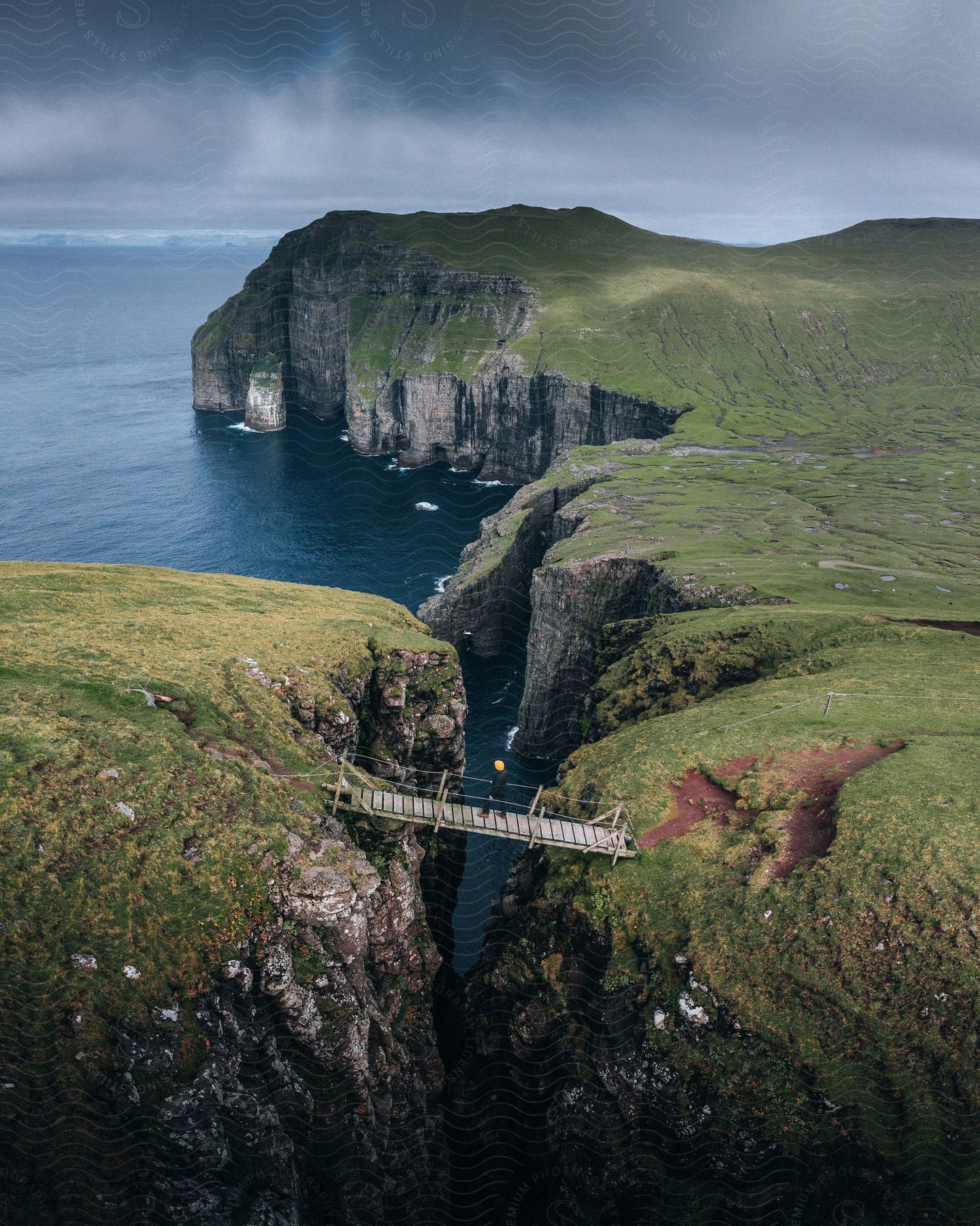 A man works on a ladder on a hill near calm water creating a picturesque scene