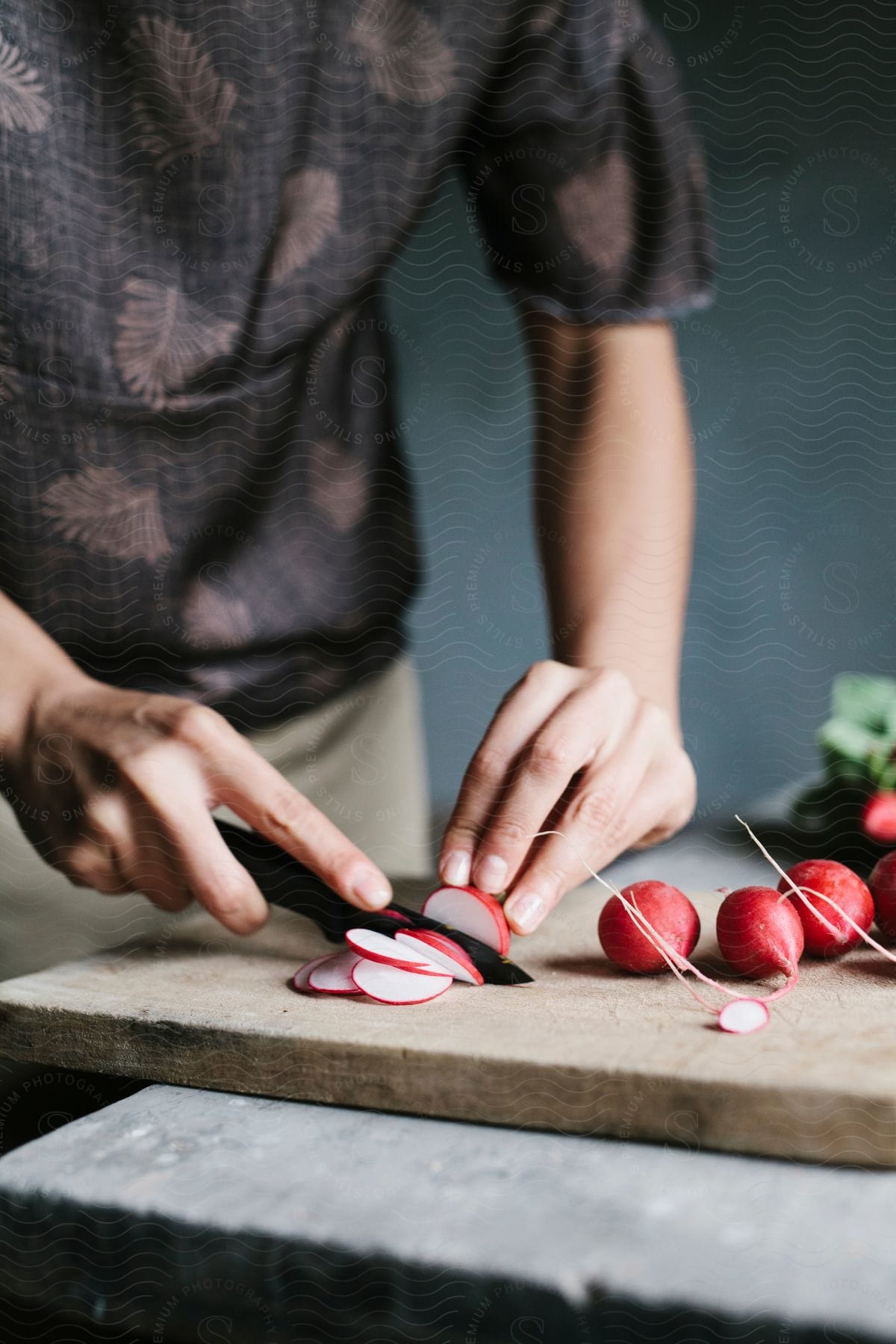 A Man Slicing A Red Fruit With A Knife On A Flat Surface In A Room