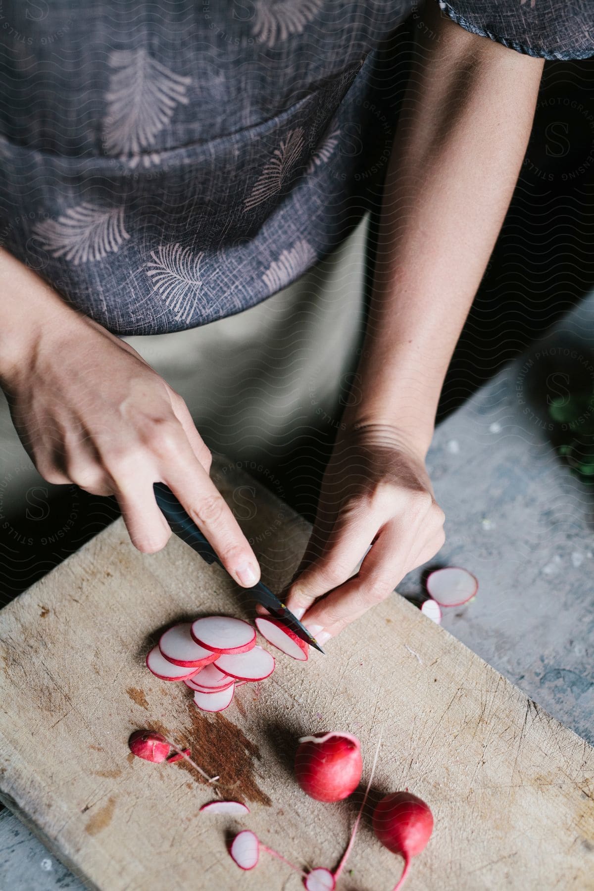 Woman cutting radishes on a wood cutting board in a kitchen