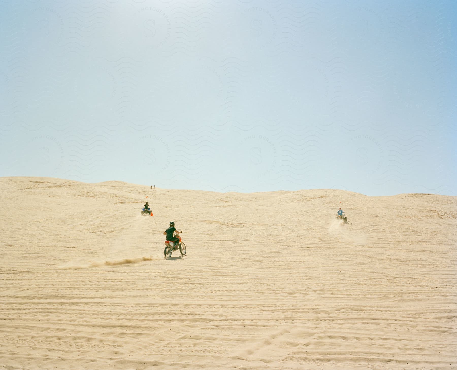 People riding motor vehicles in a sandy landscape