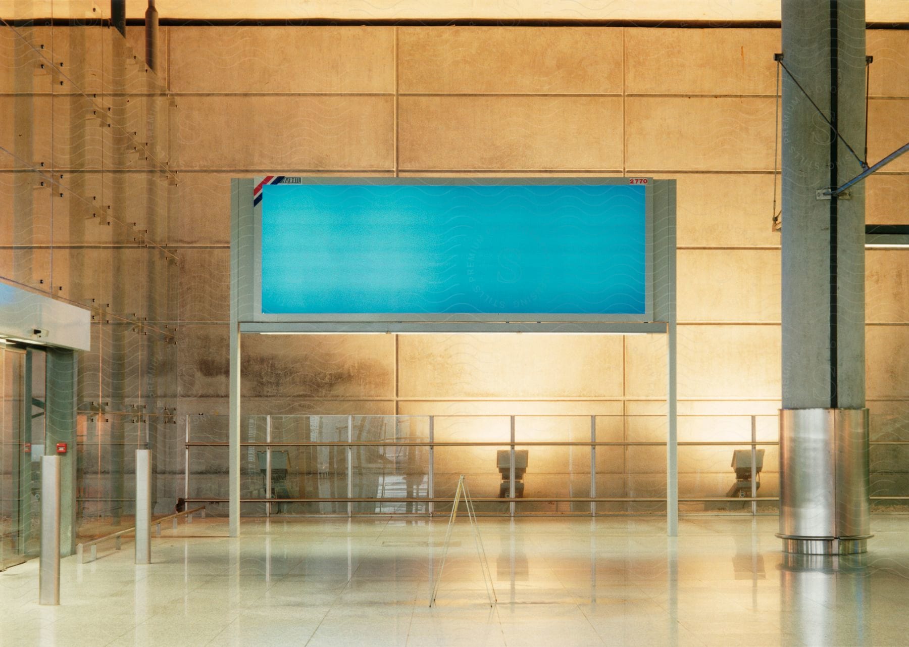 Entry door with metal detector leading to high ceilinged lobby with electronic sign