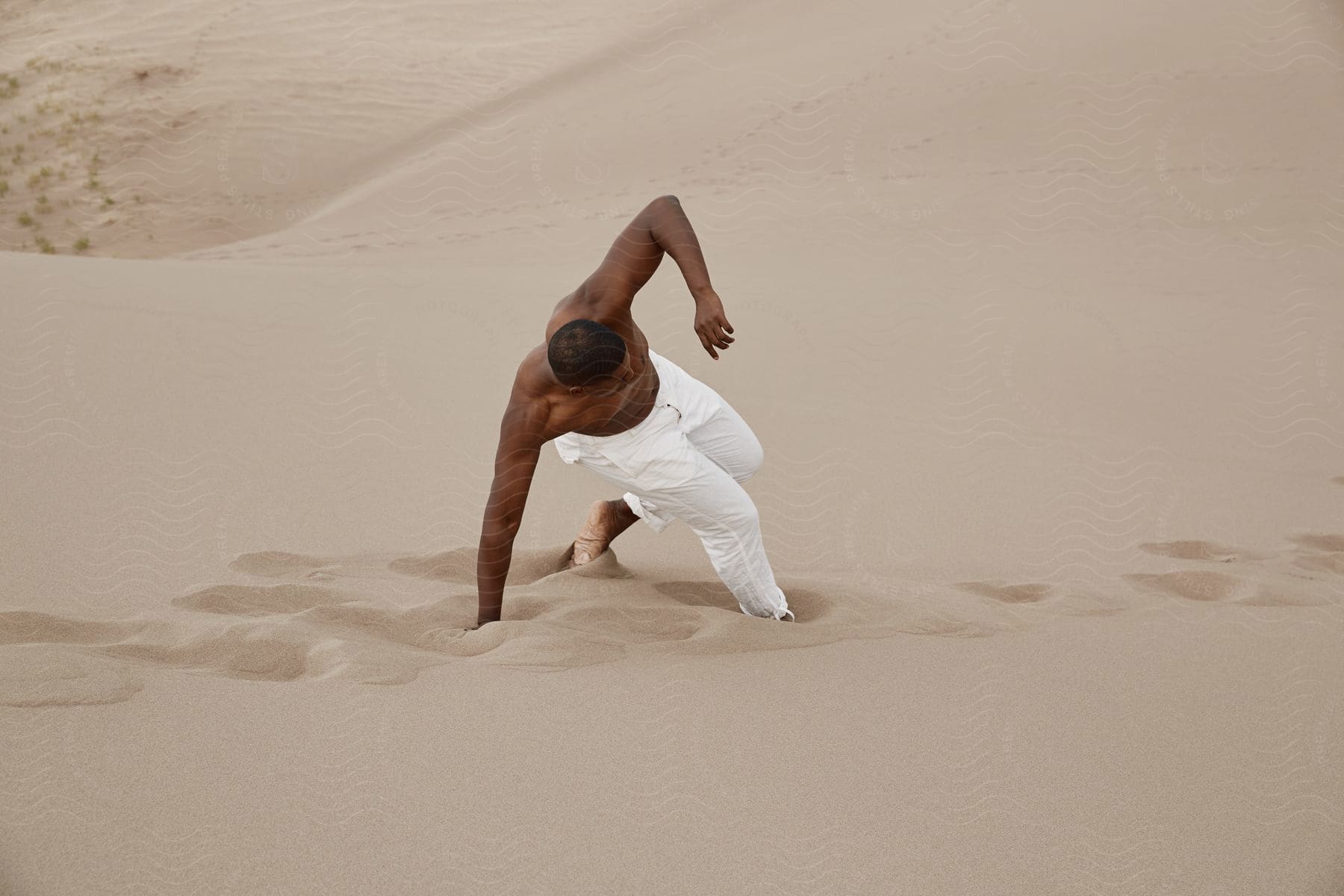 Determined man in white jeans walking through desert sand dunes