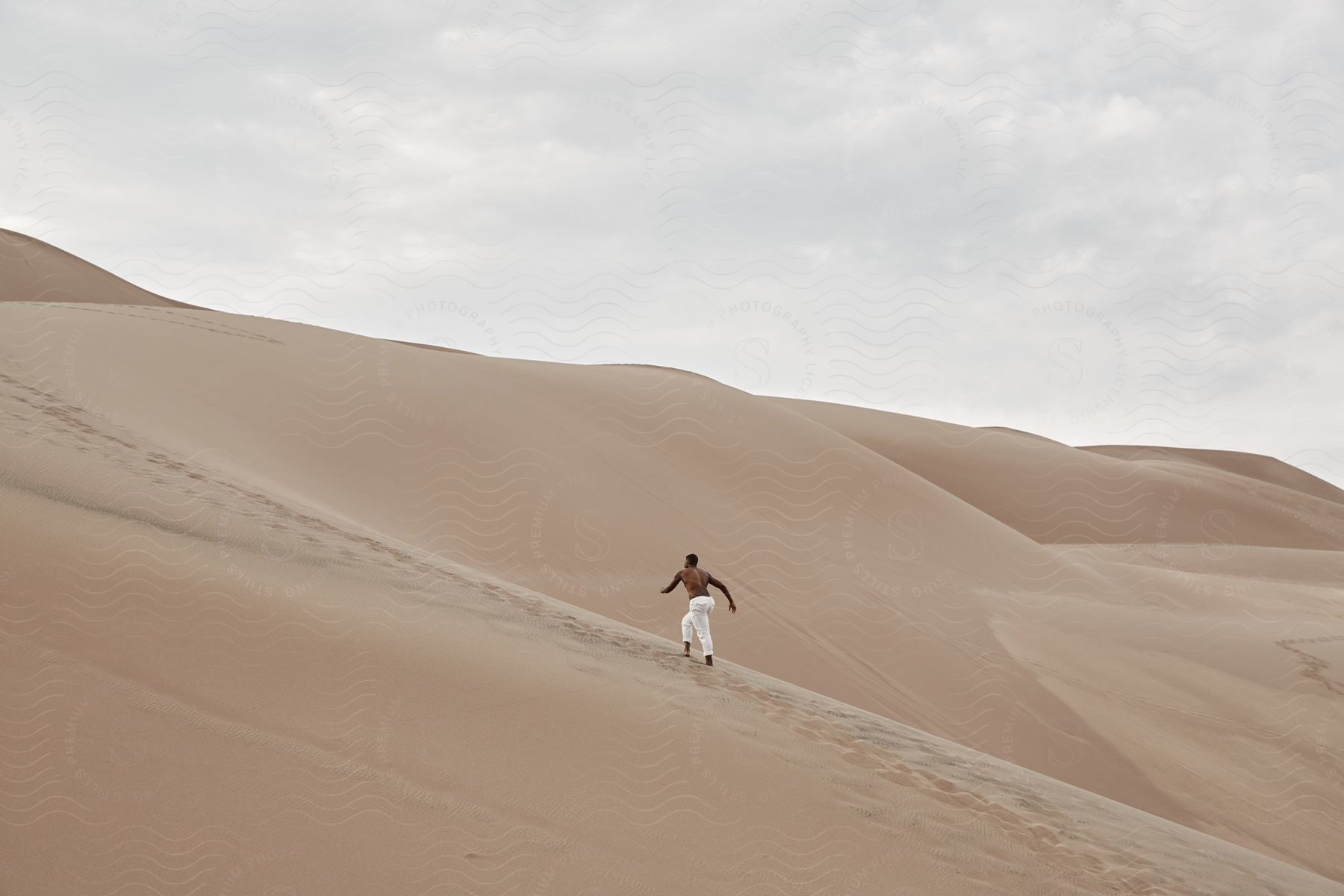 A determined man climbs barefoot on a sandy desert mountain