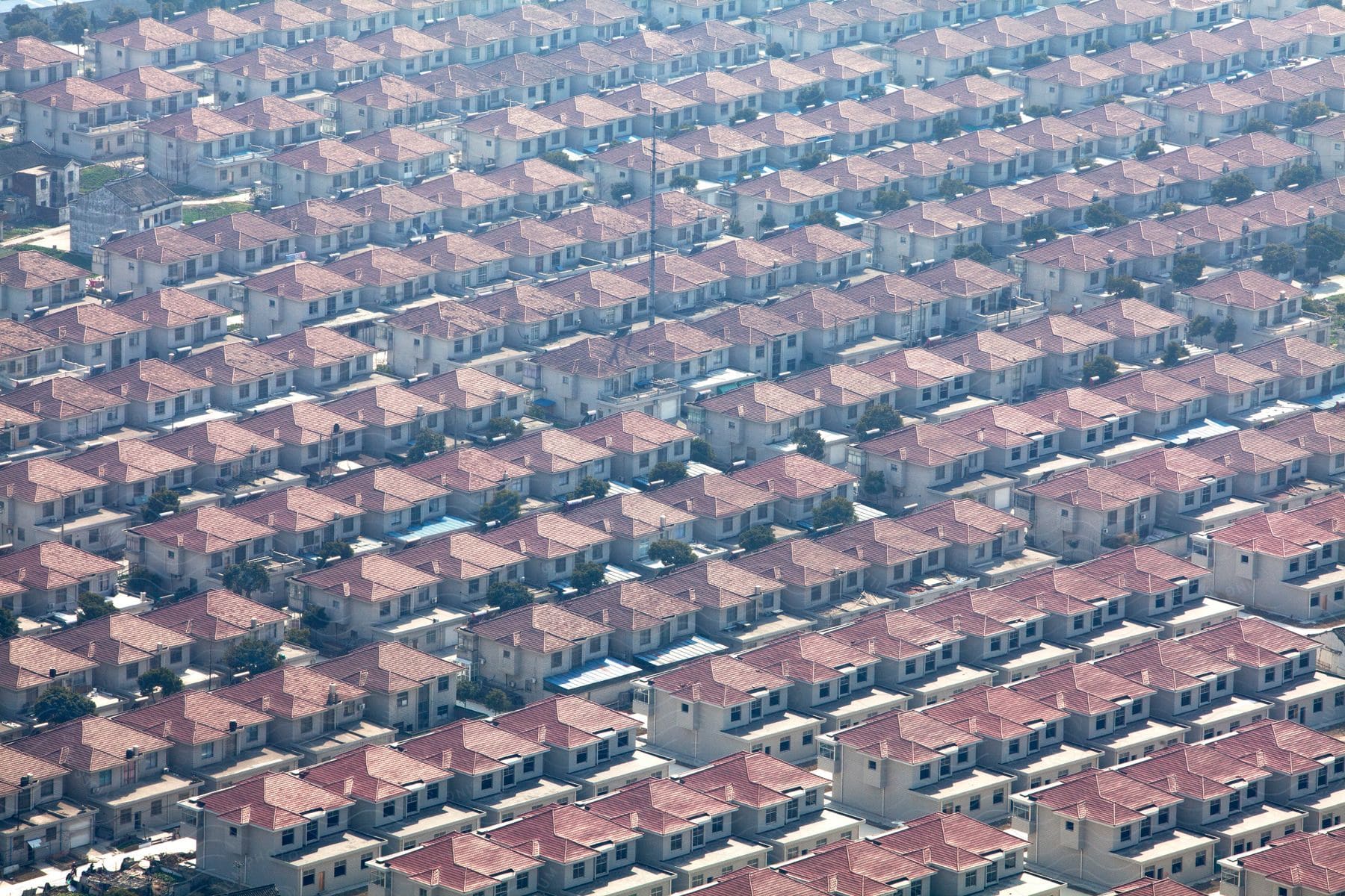 Aerial perspective of closely packed identical houses in a suburban neighborhood with parallel streets