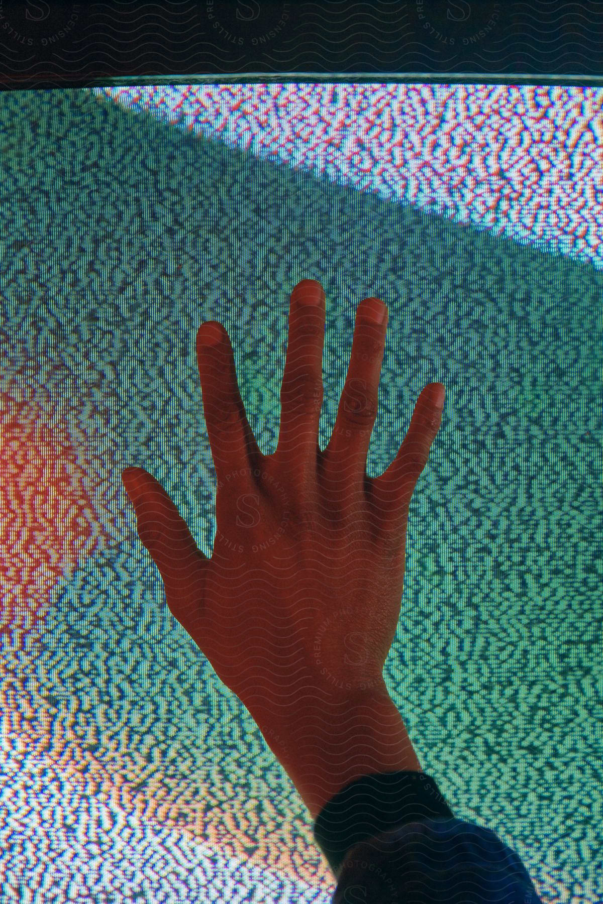 Hand on television screen in low key lighting