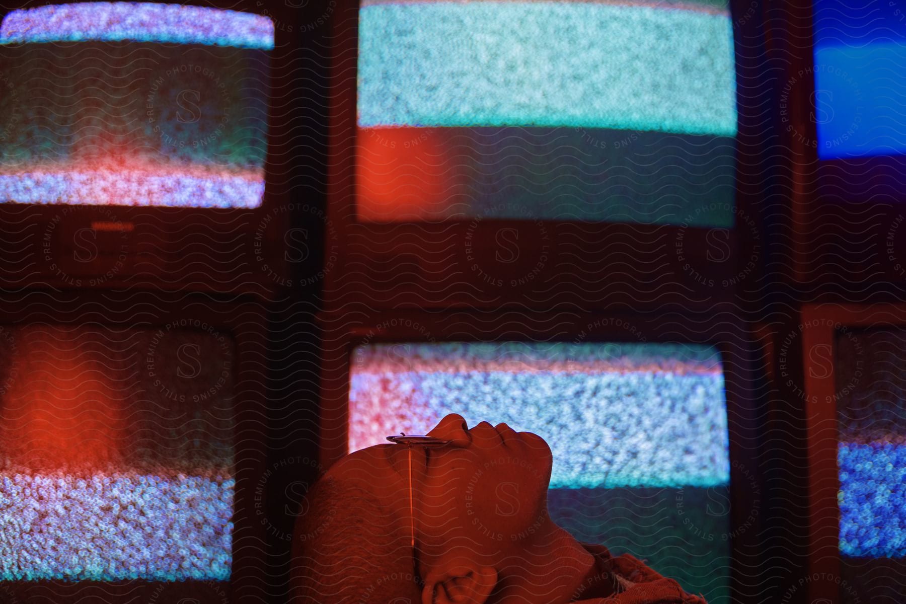 A young woman with her eyes closed illuminated by lights in a dark room