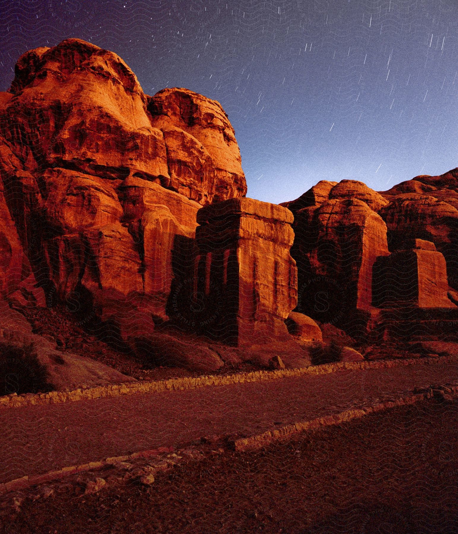 The stars shine above red rock canyons in petra jordan at night