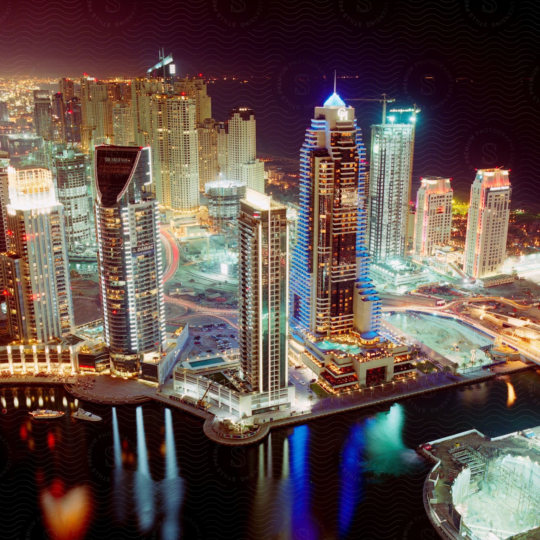 Aerial cityscape at night with illuminated skyscrapers and reflections in the water