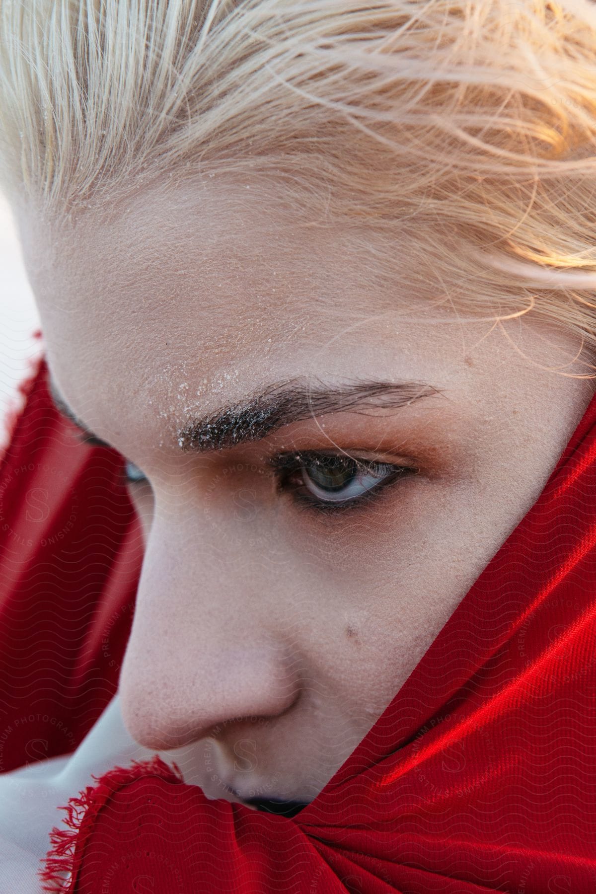 Closeup Of A Persons Face With Blonde Hair Partially Wrapped In A Bright Red Shawl