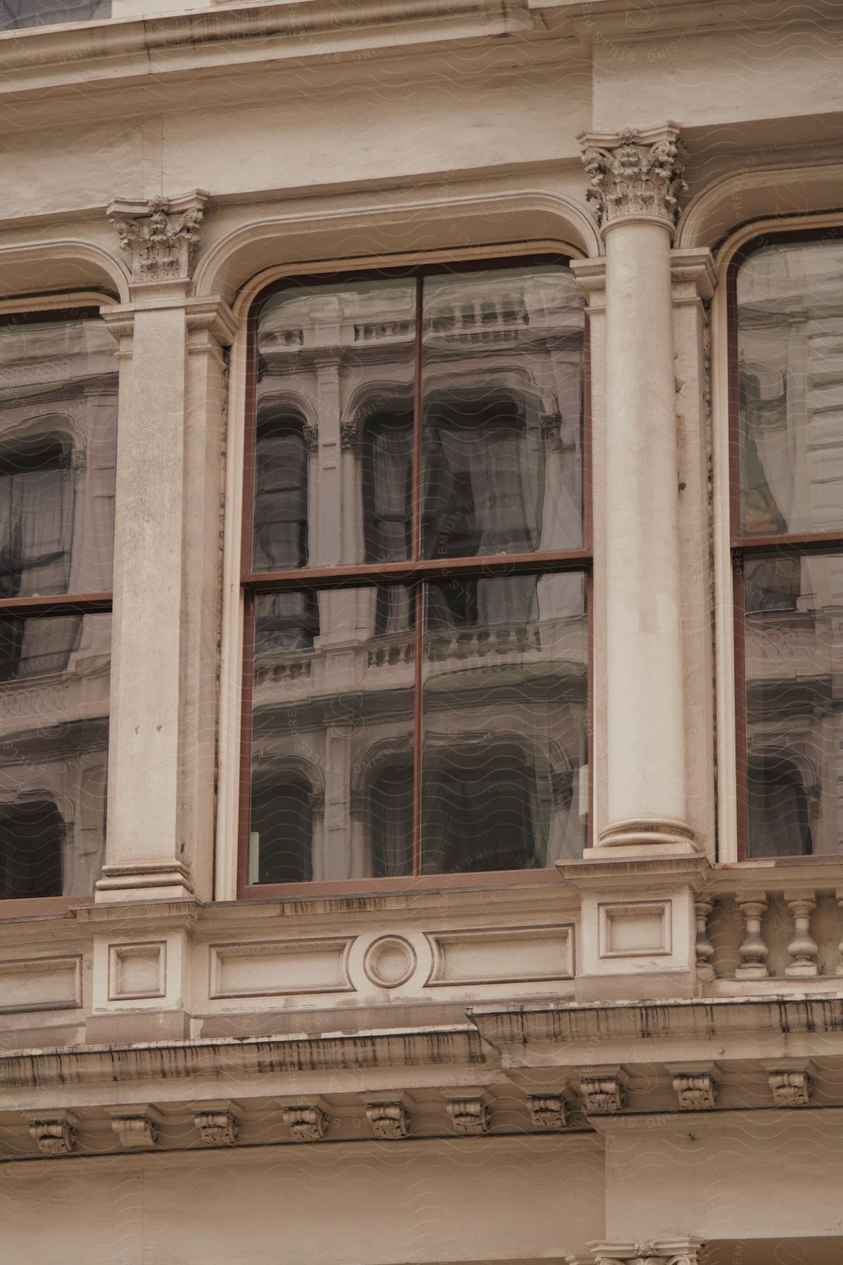 An ornate window reflects neighboring luxurious windows on a building facade