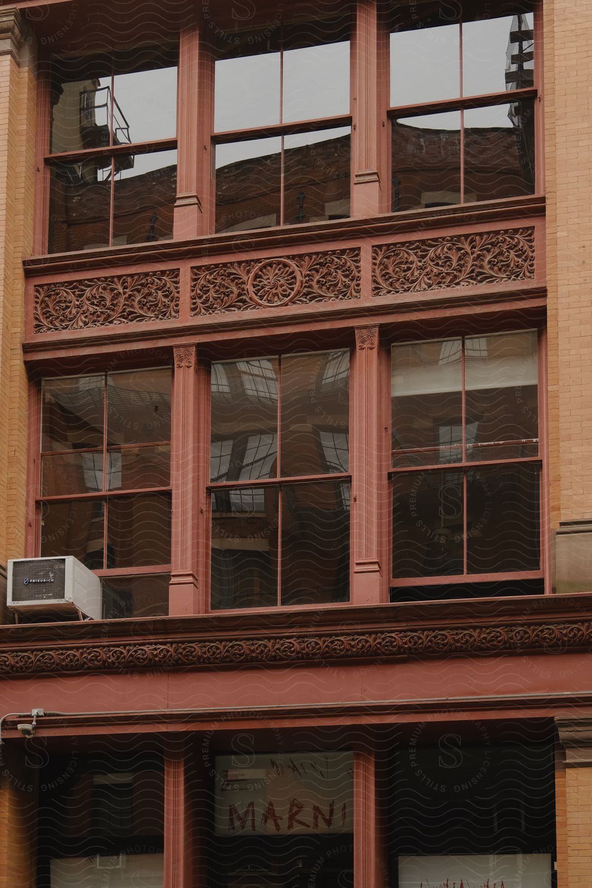 Rectangular windows on a brown building with an air conditioner hanging out one window