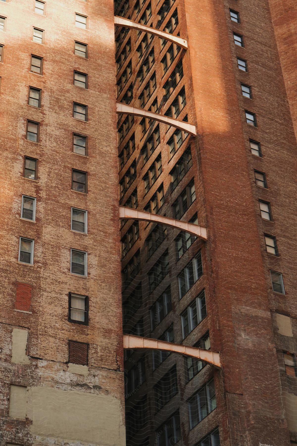 Two old brown highrise apartment buildings stand side by side supported by metallic bars and characterized by dusty windows